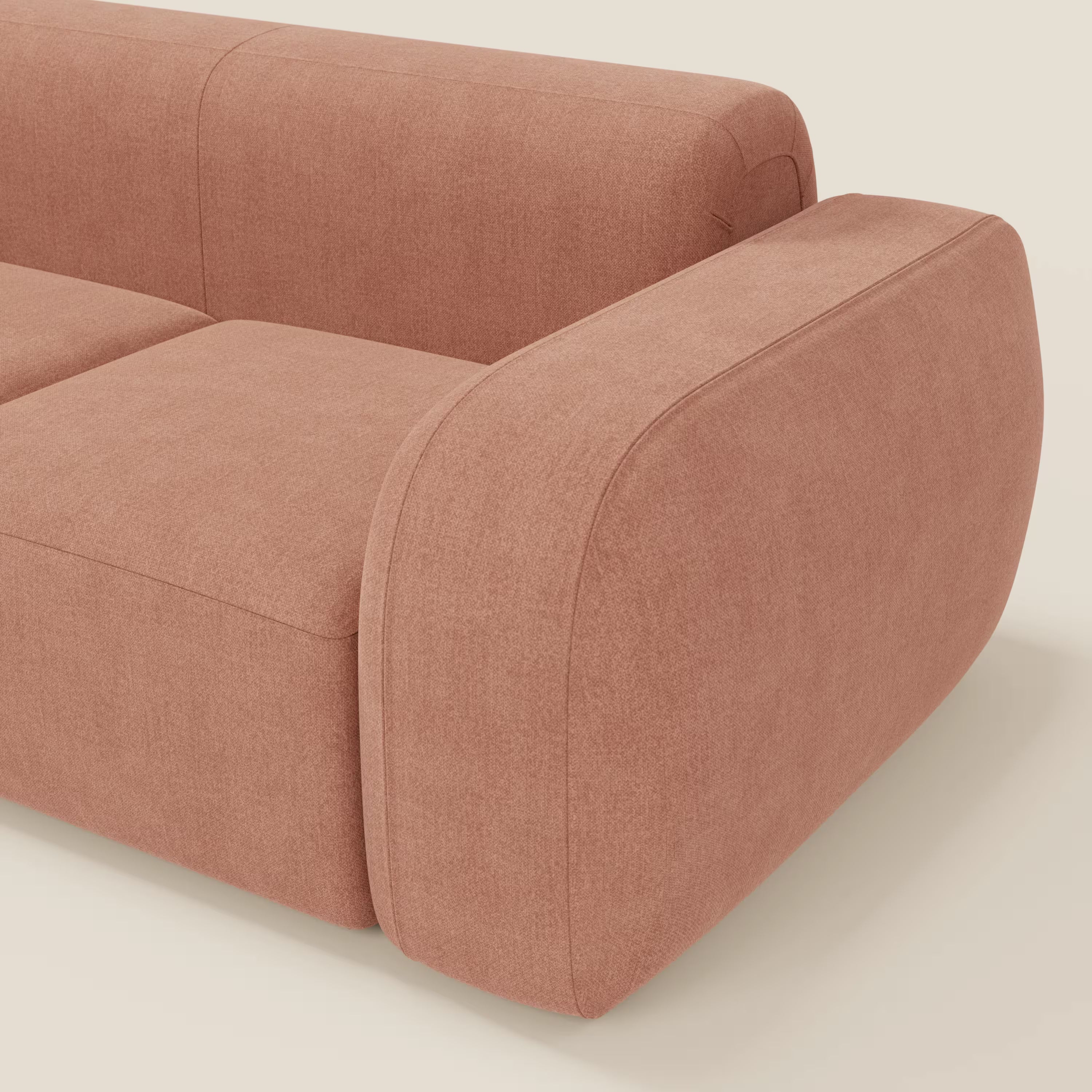 Un primo piano del divano componibile BonBon - Composizione Spaccamattone di Divani.Store in tessuto antimacchia T23 pesca mostra i braccioli arrotondati e imbottiti e le cuciture ridotte al minimo, evidenziando il suo design moderno e unico su uno sfondo chiaro.