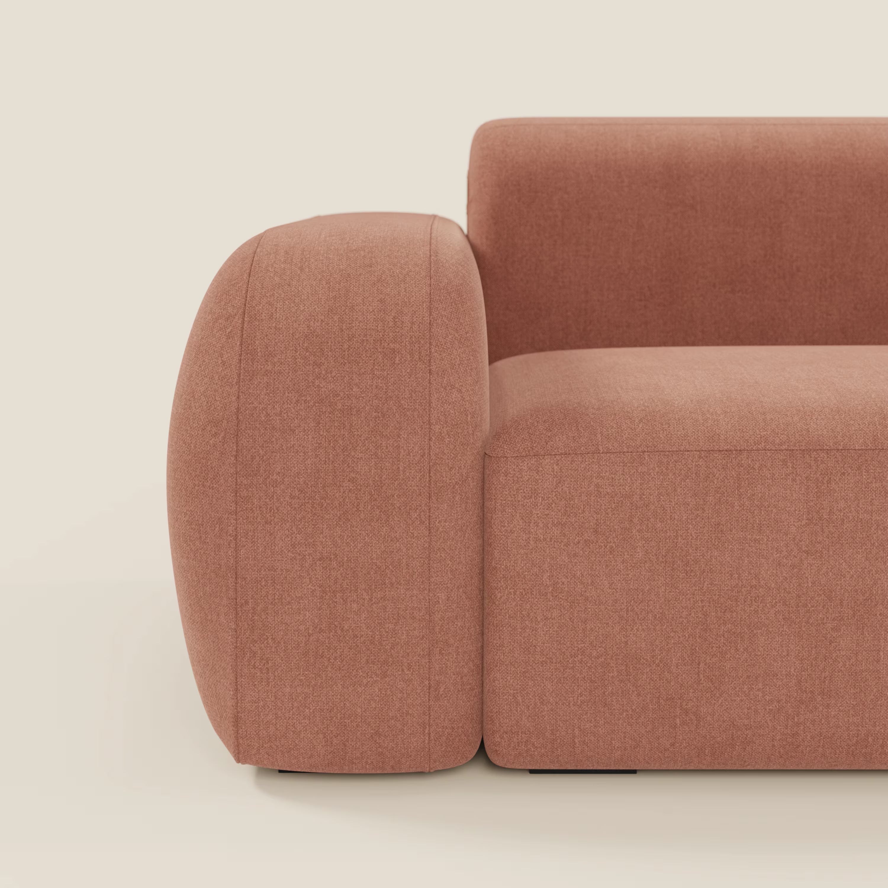 Un primo piano del BonBon Divano modulare componibile - Composizione Spaccamattone di Divani.Store in smacchiabile T23 pesca, mette in evidenza i bordi arrotondati e l'imbottitura liscia su uno sfondo chiaro, concentrandosi sul bracciolo sinistro, sulla seduta e sullo schienale.