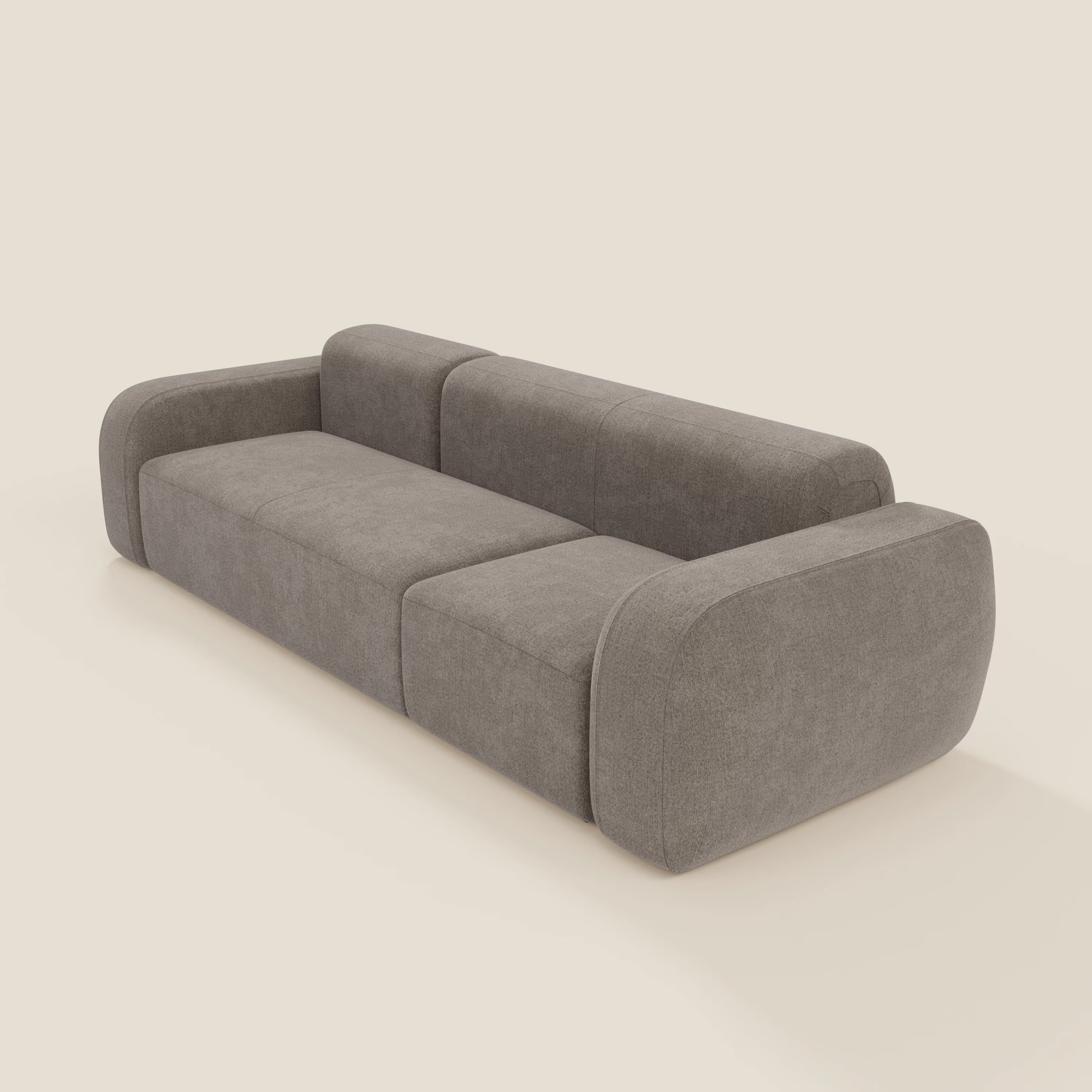 Il BonBon Divano componibile - Composizione Spaccamattone in tessuto smacchiabile T23 talpa di Divani.Store è un divano moderno grigio con braccioli e schienale arrotondati e imbottiti, dalla silhouette bassa e squadrata, con tre posti a sedere su sfondo beige chiaro.
