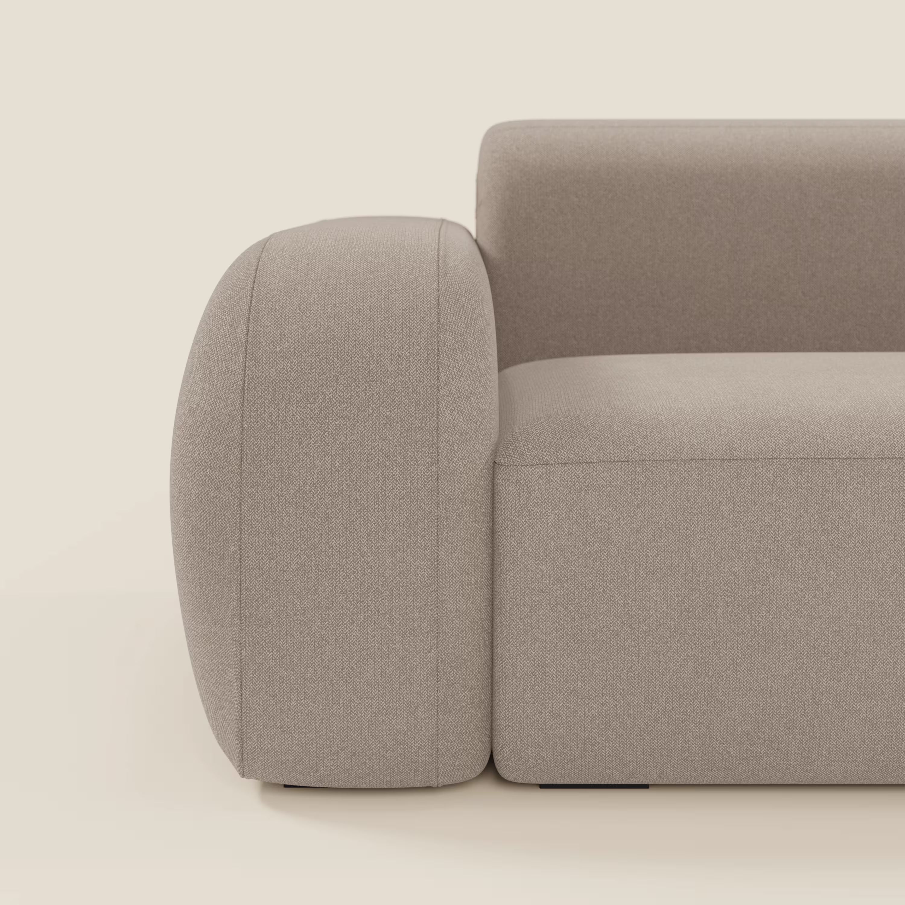 Primo piano del BonBon Divano componibile - Composizione Spaccamattone in tessuto smacchiabile T23 tortora di Divani.Store, con braccioli spessi e arrotondati e linee minimali, su uno sfondo bianco sporco e morbido.