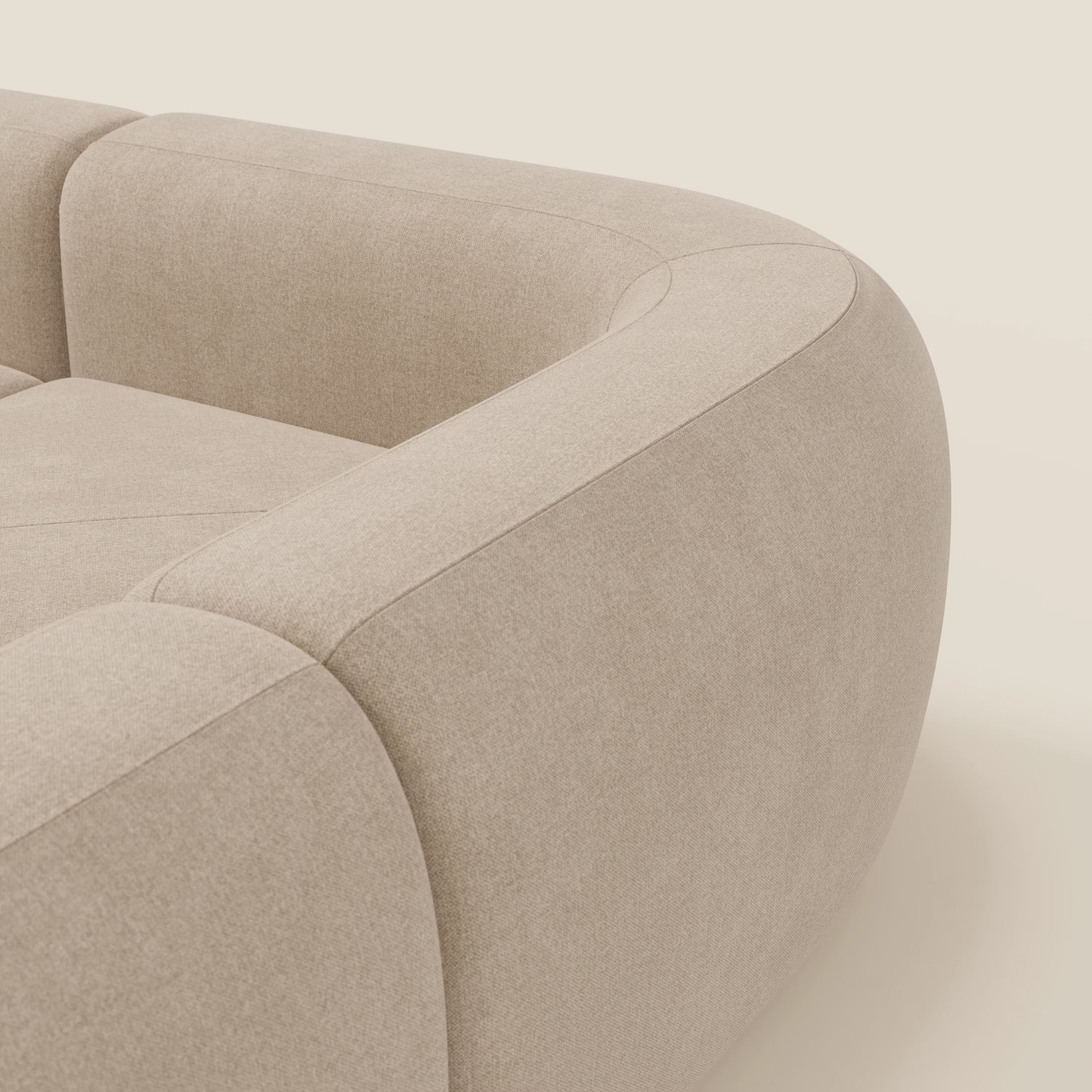 Un primo piano del divano angolare componibile e modulare BonBon di Divani.Store, in tessuto smacchiabile T23 beige, mostra i braccioli spessi e arrotondati, il tessuto morbido e l'elegante design contemporaneo su uno sfondo chiaro.