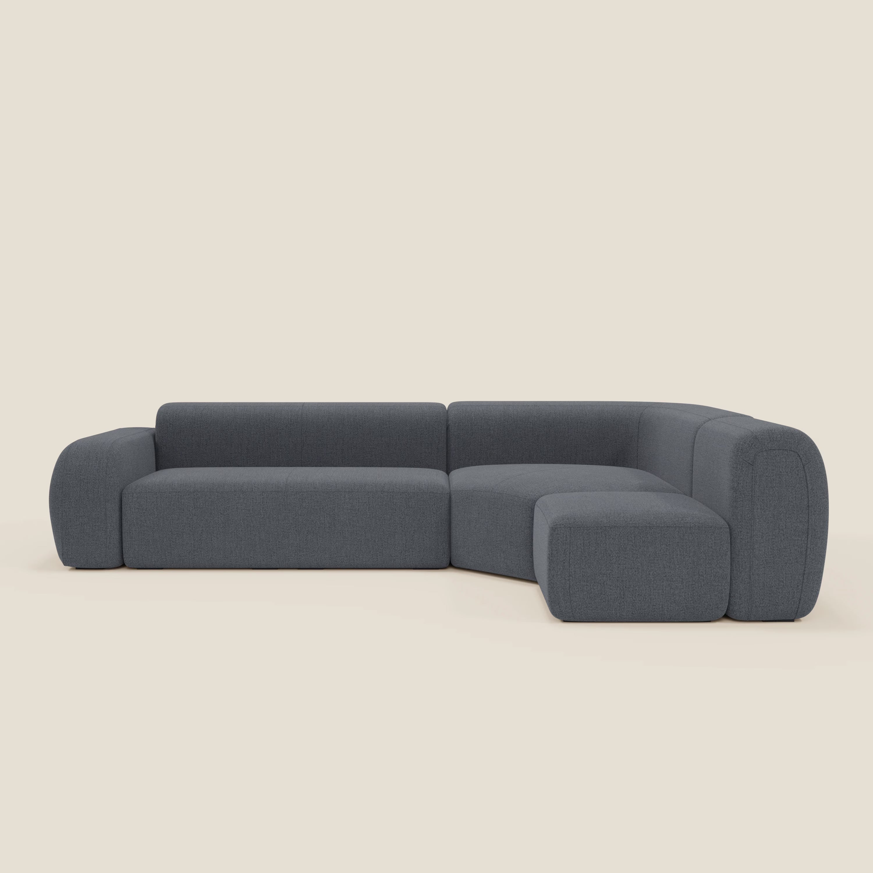 Il divano angolare componibile e modulare BonBon di Divani.Store, in tessuto smacchiabile T23 blu grafite, è caratterizzato da un design ampio e moderno con bordi arrotondati, schienale basso e sfondo beige chiaro.