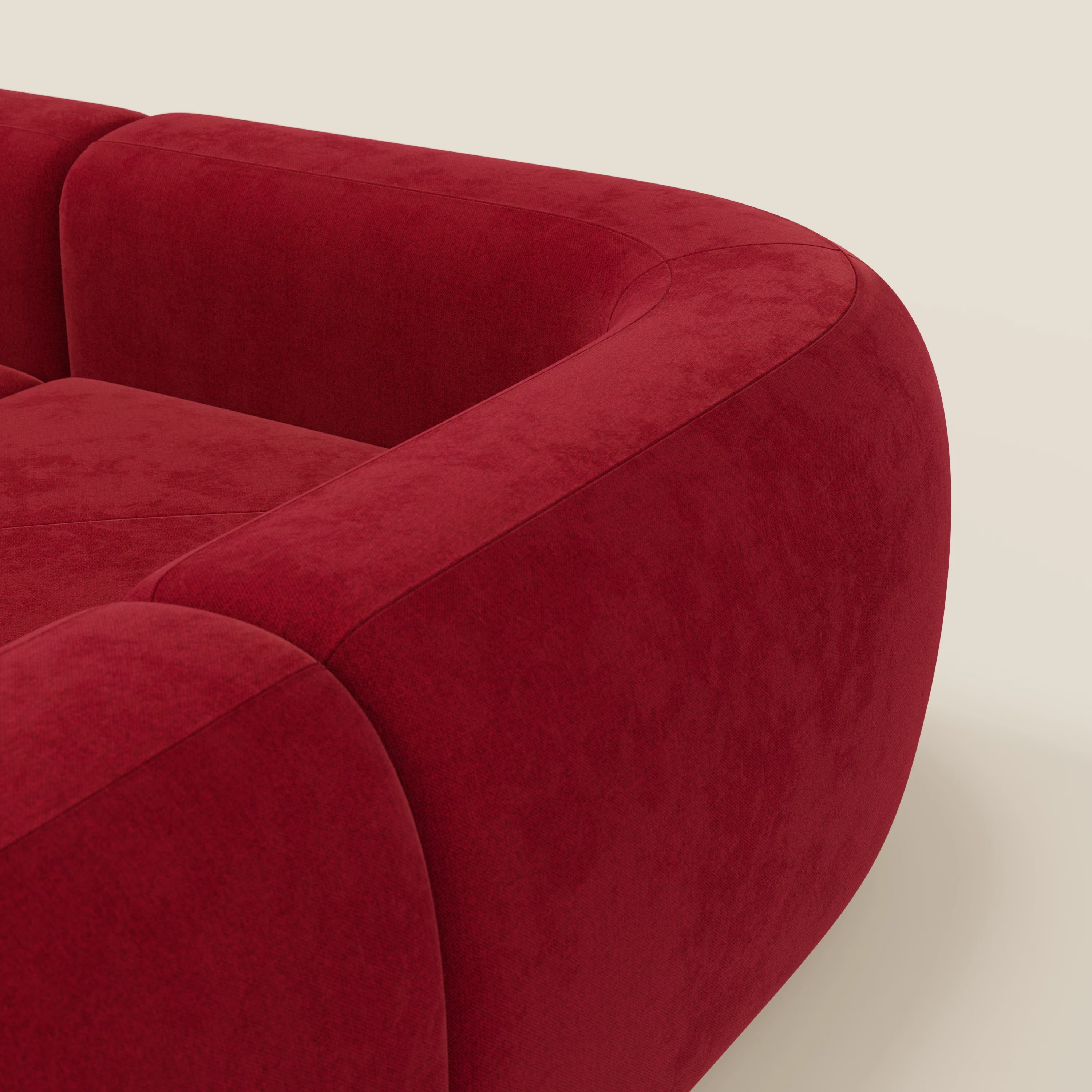 Primo piano del divano angolare componibile e modulare BonBon di Divani.Store in smacchiabile T23 bordeaux, caratterizzato da braccioli morbidi e da un design morbido e curvilineo che ne esalta il colore ricco e lo stile contemporaneo.