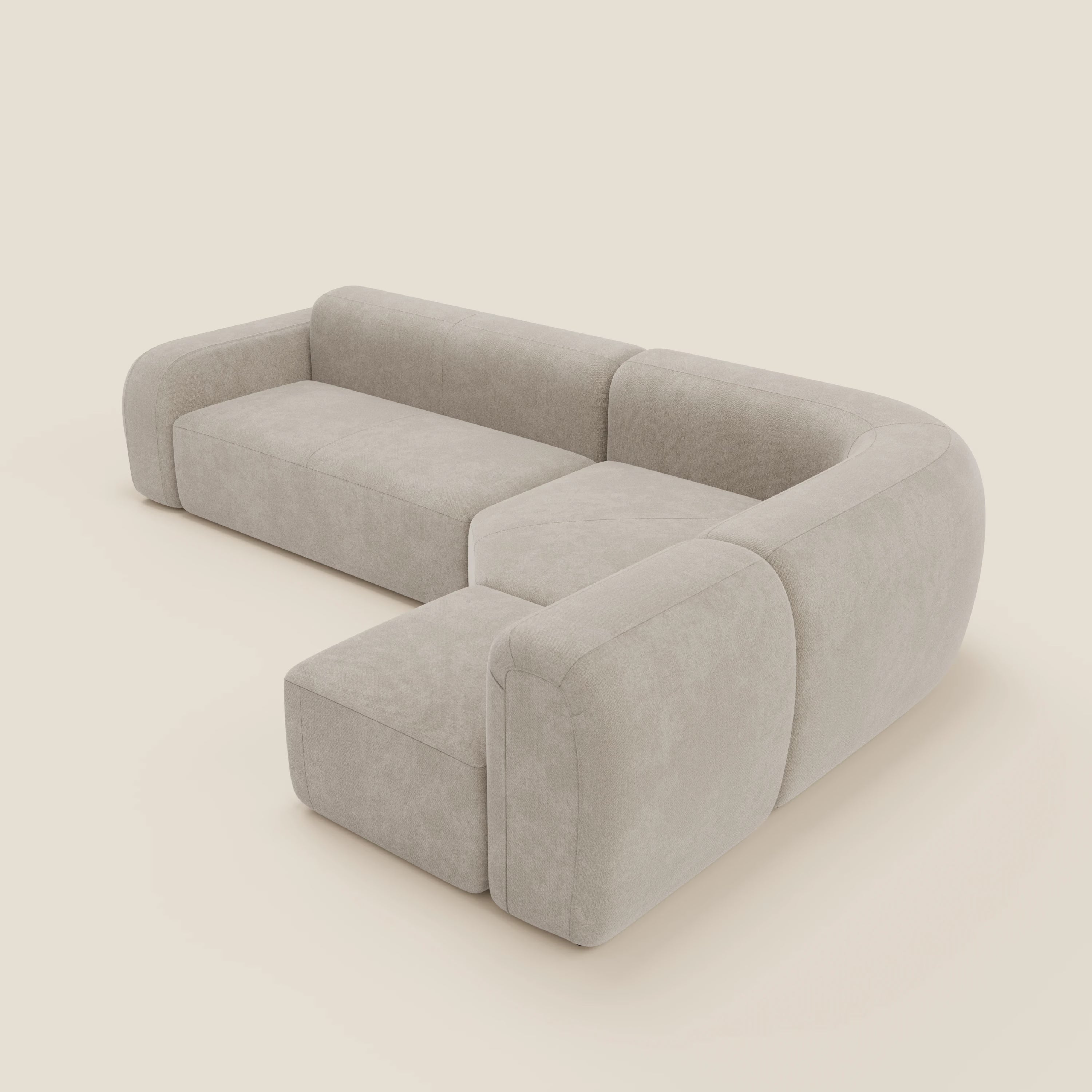 Il divano angolare componibile e modulare BonBon di Divani.Store in tessuto smacchiabile T23 panna presenta un design moderno con angoli arrotondati, cuscini morbidi e chaise longue, su fondo bianco sporco.