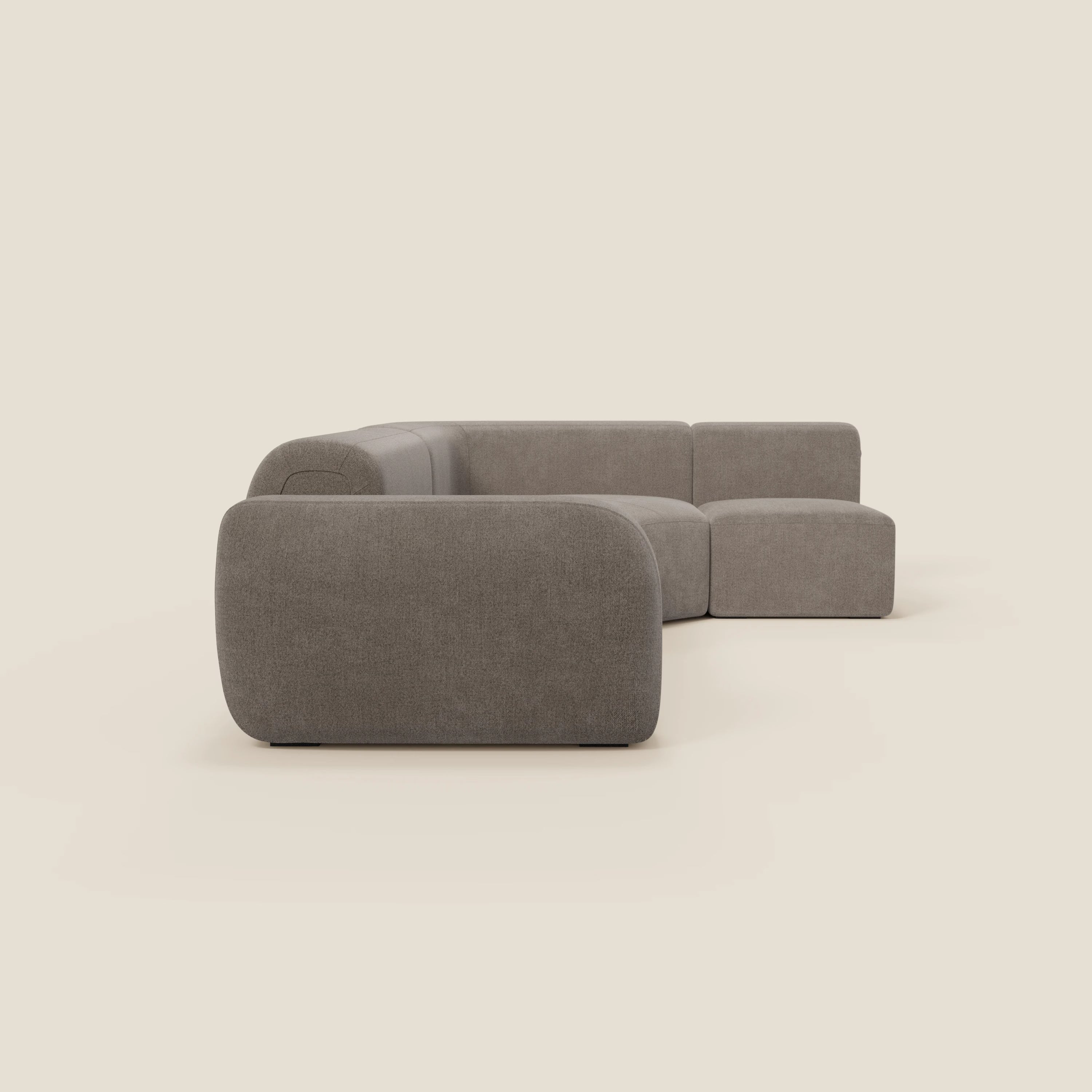 Il divano angolare componibile e modulare BonBon di Divani.Store è caratterizzato da bordi arrotondati e da un tessuto in talpa T23 morbido e smacchiabile. Questo moderno divano a L si staglia su uno sfondo beige chiaro.