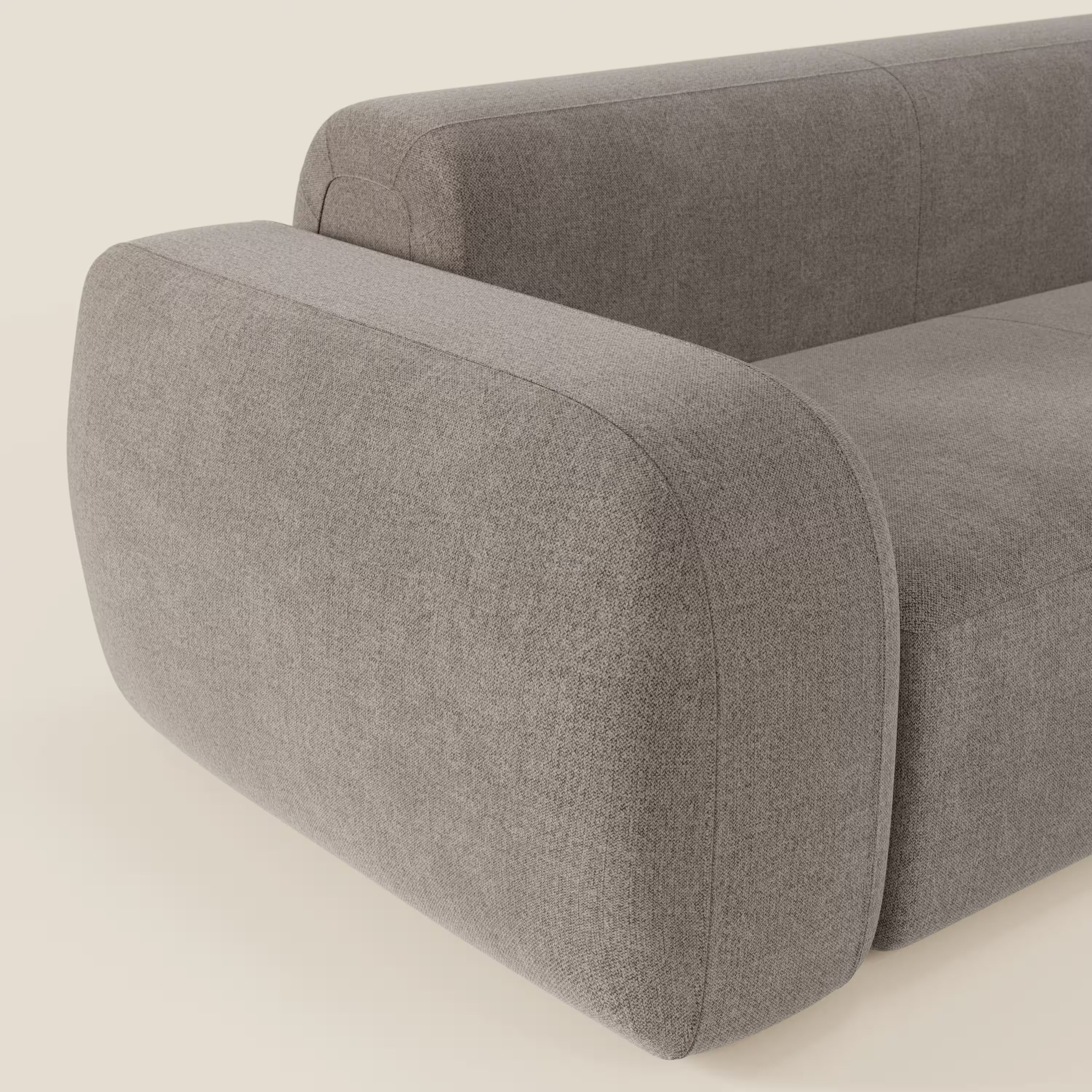 Primo piano del divano angolare componibile e modulare BonBon di Divani.Store, con braccioli e schienale spessi e arrotondati, rivestiti in tessuto smacchiabile T23 talpa. Il design minimalista è caratterizzato da curve morbide e linee pulite su uno sfondo chiaro.