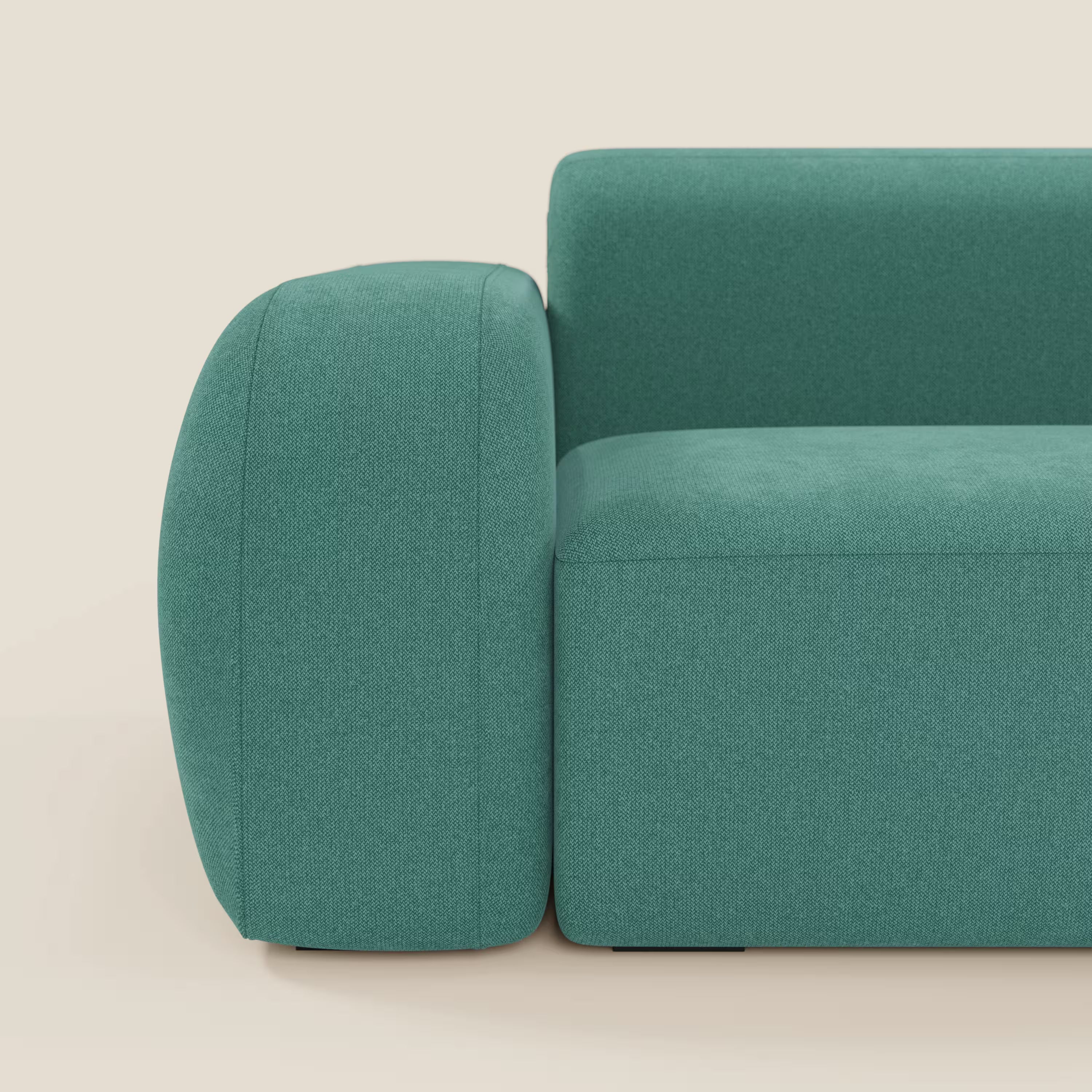 Un primo piano del divano angolare componibile e modulare BonBon di Divani.Store in tessuto smacchiabile T23 verde acqua mostra il bracciolo sinistro e la seduta. La forma squadrata e minimalista con bordi arrotondati spicca su uno sfondo color crema.
