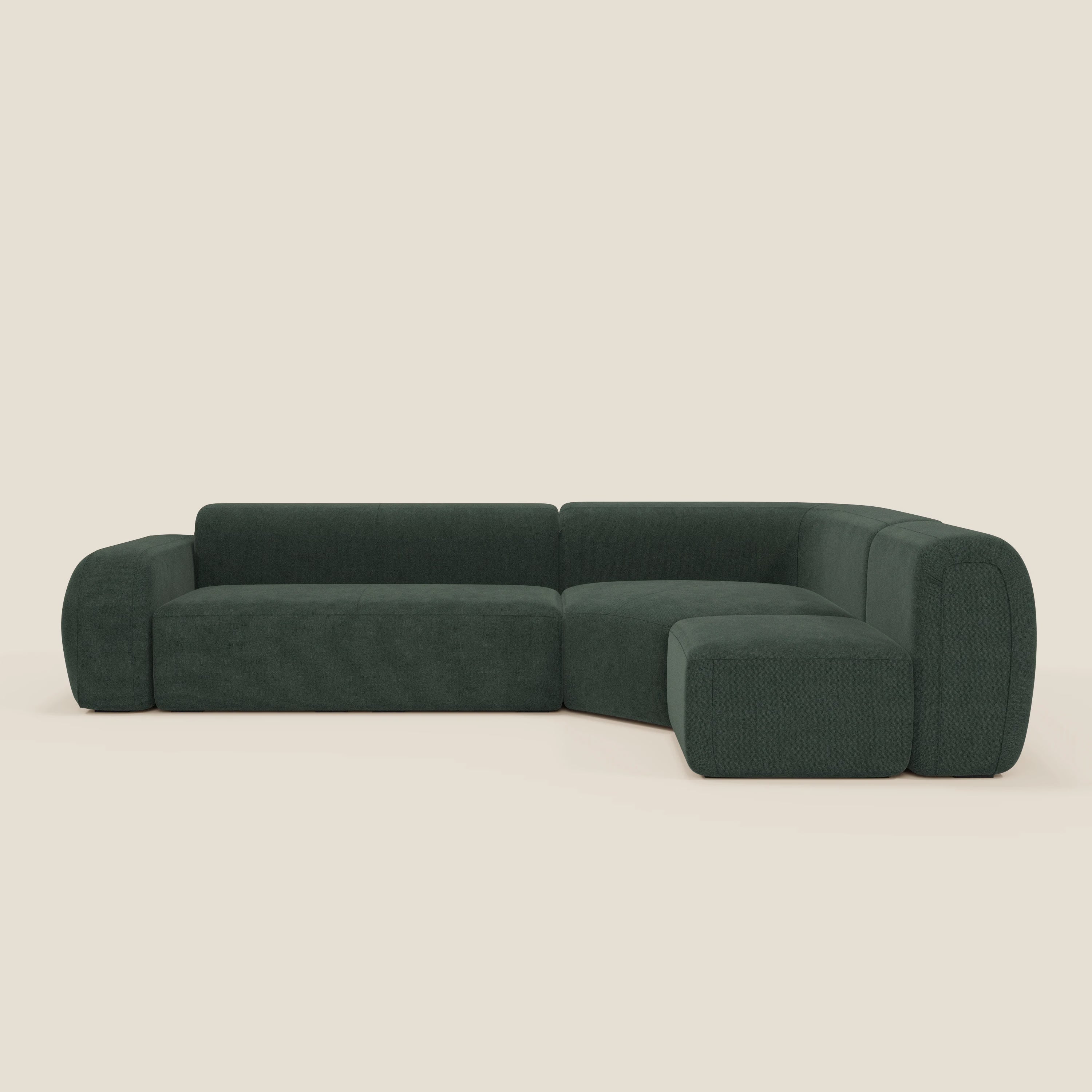 Il divano BonBon angolare componibile e modulare di Divani.Store in tessuto smacchiabile T23 verde è un divano componibile moderno a forma di L con schienale basso, braccioli e bordi di seduta arrotondati a blocchi, presentato su uno sfondo bianco sporco.