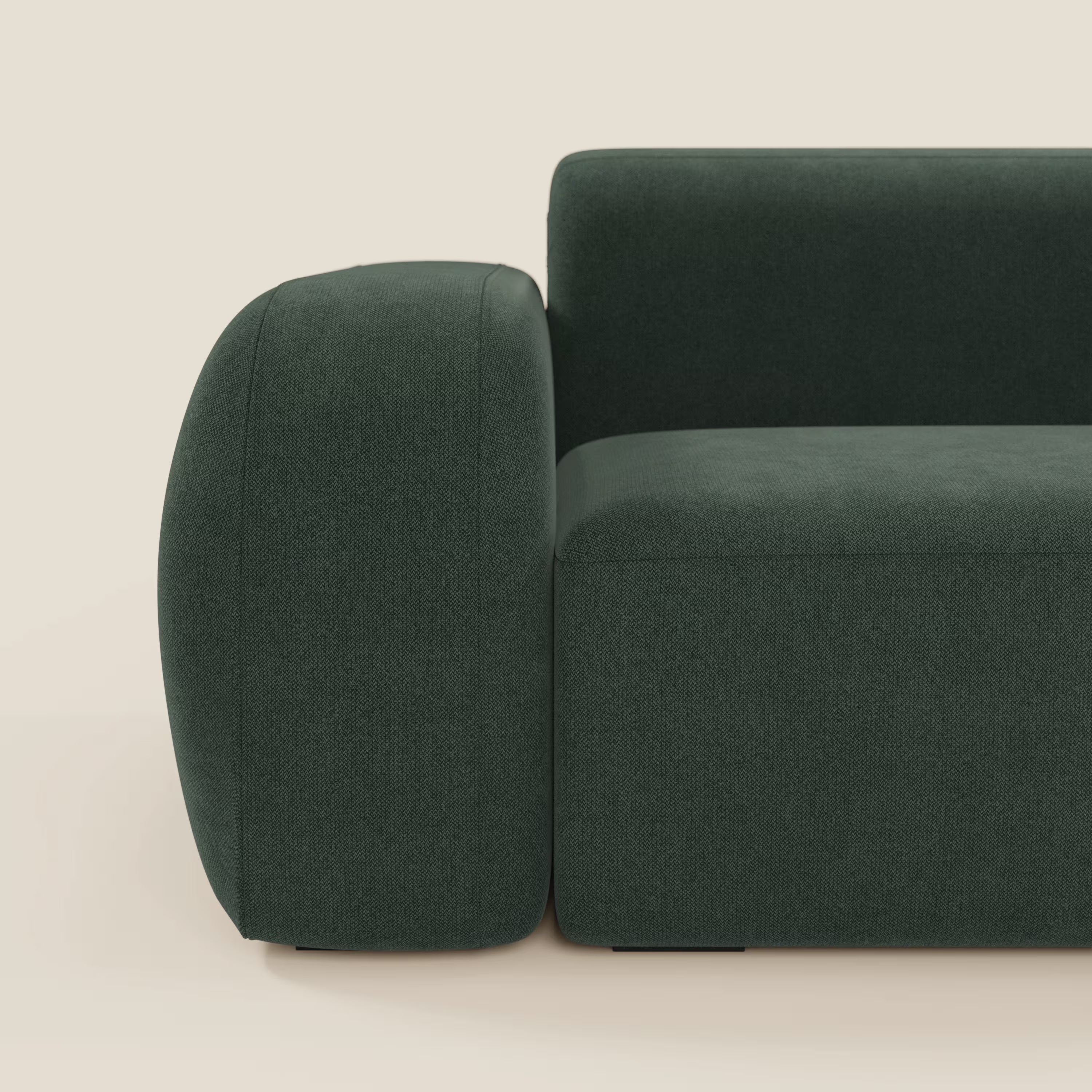 Un primo piano del divano BonBon angolare componibile e modulare in tessuto smacchiabile T23 verde di Divani.Store mostra il bracciolo sinistro e la seduta, con cuscini rettangolari e morbidi. Realizzato in Italia, è inserito in un semplice sfondo beige.