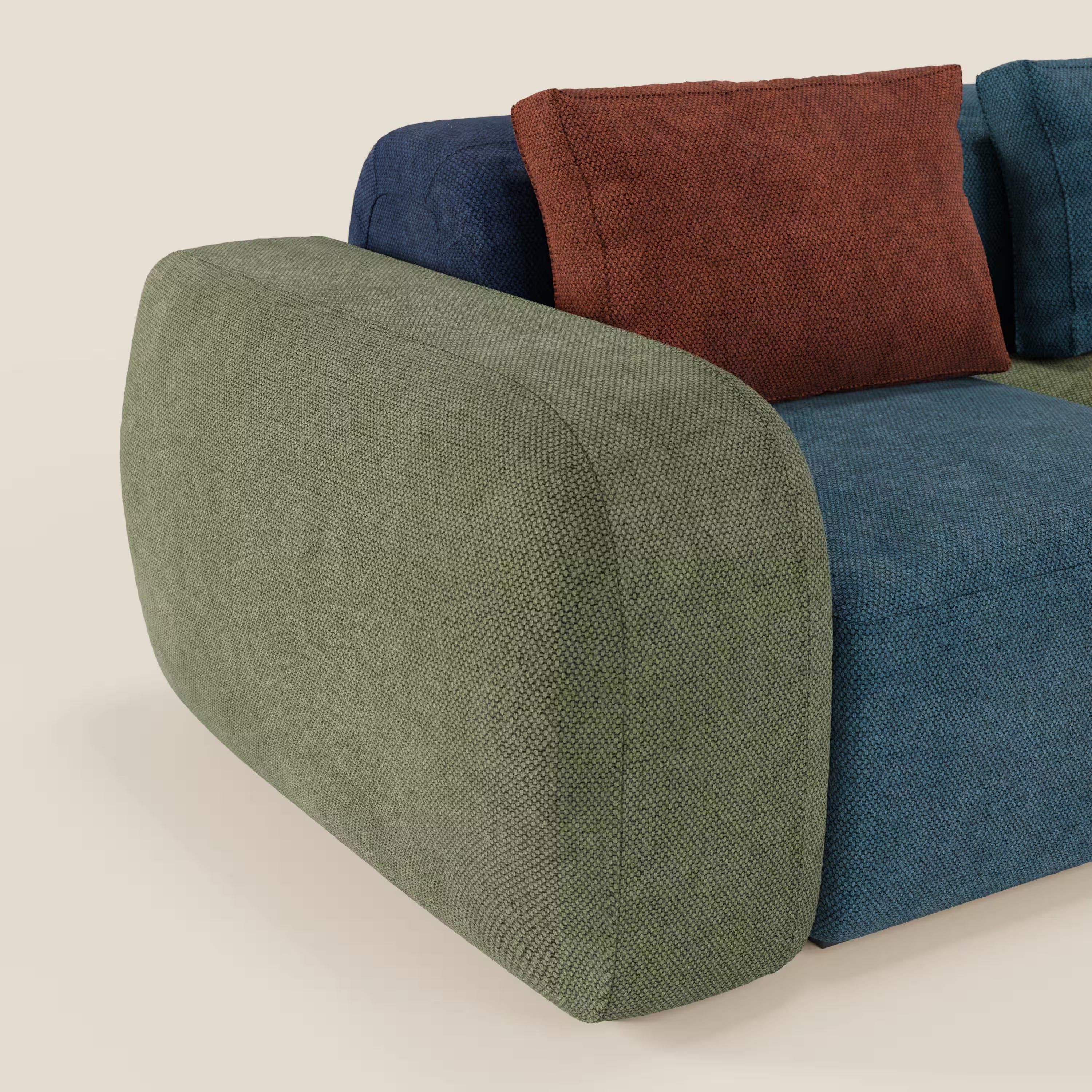 Il divano componibile BonBon 3 sedute - edizione Grande Fratello di Divani.Store è caratterizzato da un tessuto strutturato con bracciolo verde oliva, seduta blu, schienale blu navy e cuscino da lancio color ruggine su sfondo beige chiaro. Prodotto in Italia.