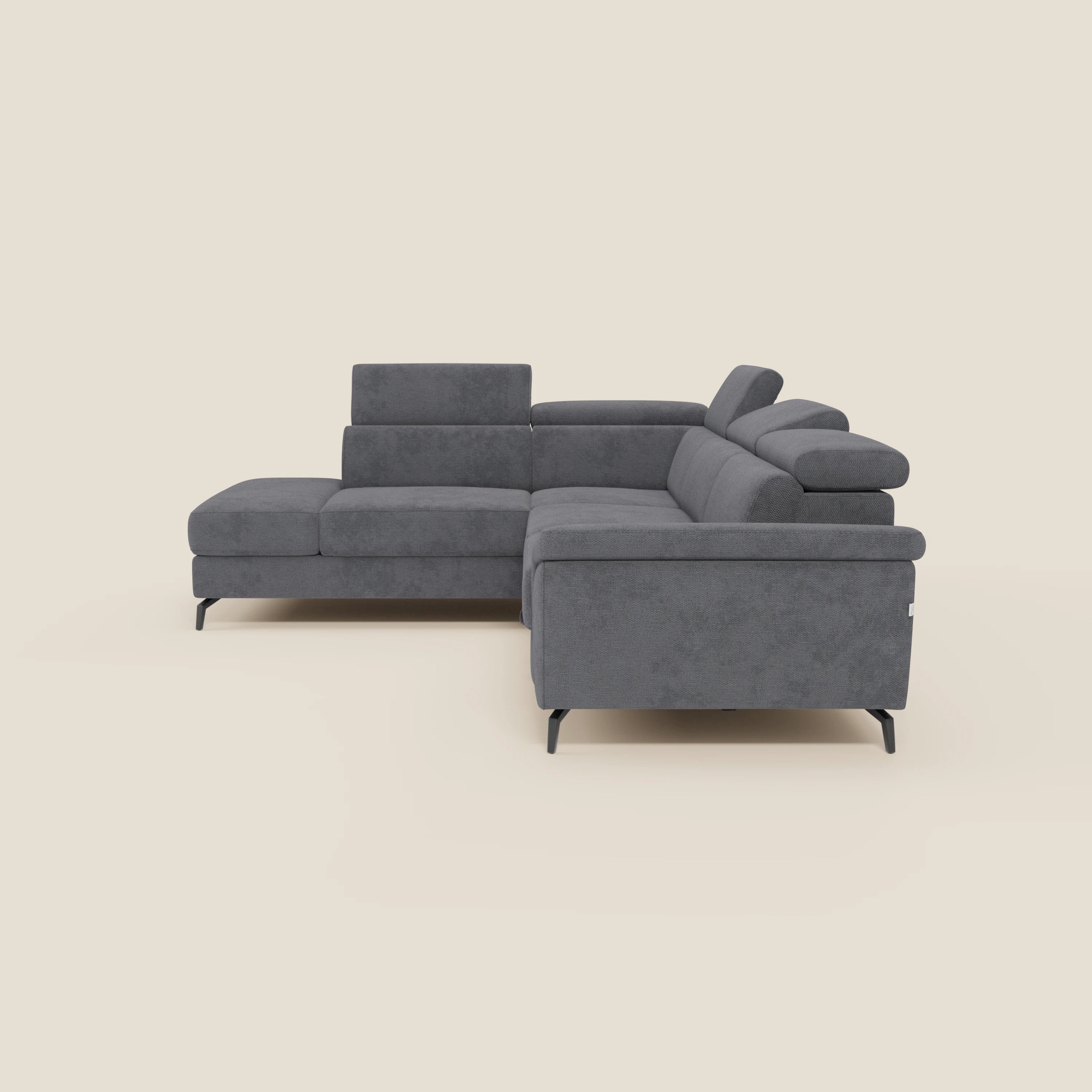 Il divano angolare estraibile Estro Divano di Divani.Store è caratterizzato da poggiatesta reclinabili, ampi braccioli e gambe in metallo nero. Rivestito in tessuto impermeabile grigio scuro T14, il suo design moderno a forma di L spicca su uno sfondo beige chiaro.