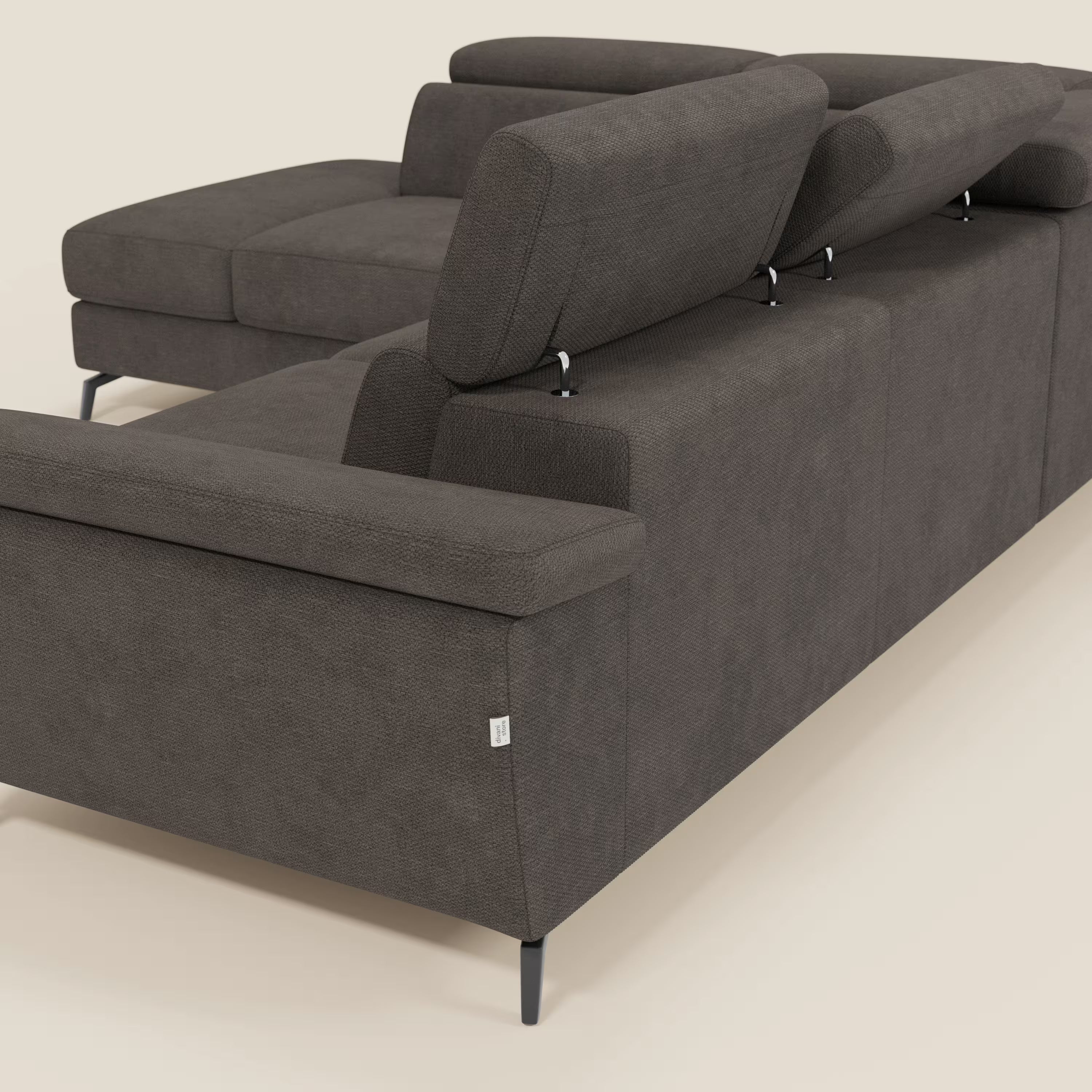 Il divano angolare estraibile Estro di Divani.Store è dotato di poggiatesta reclinabili in tessuto impermeabile marrone T14, di sottili gambe in metallo nero e mostra il suo rivestimento testurizzato e la vista posteriore con poggiatesta in rilievo su uno sfondo chiaro.