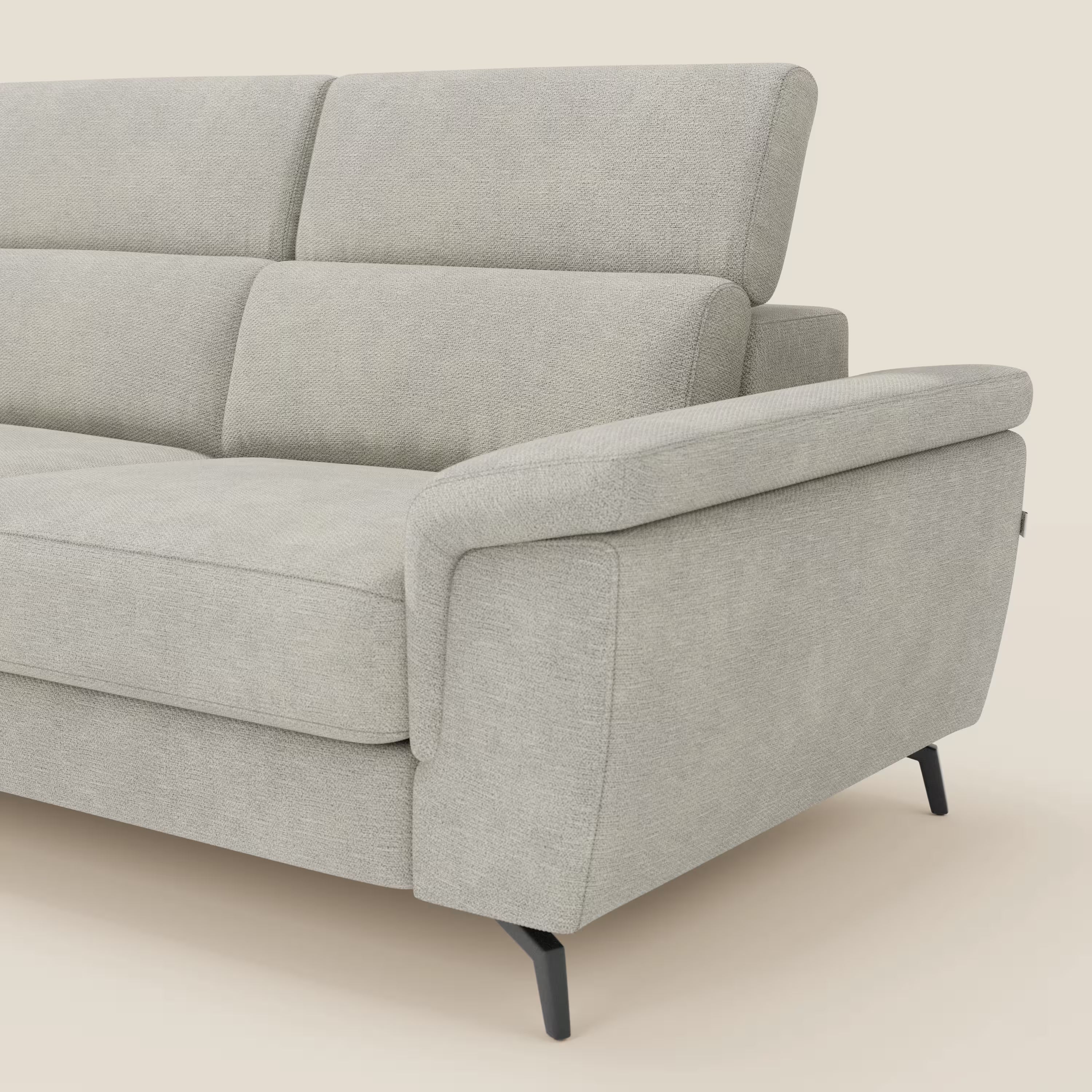 Il divano angolare estraibile Estro Divano di Divani.Store è caratterizzato da spessi cuscini, poggiatesta regolabili e ampi braccioli imbottiti in tessuto impermeabile T14 panna. Le sottili gambe nere completano il look. Solo una parte del divano è visibile su uno sfondo color crema.