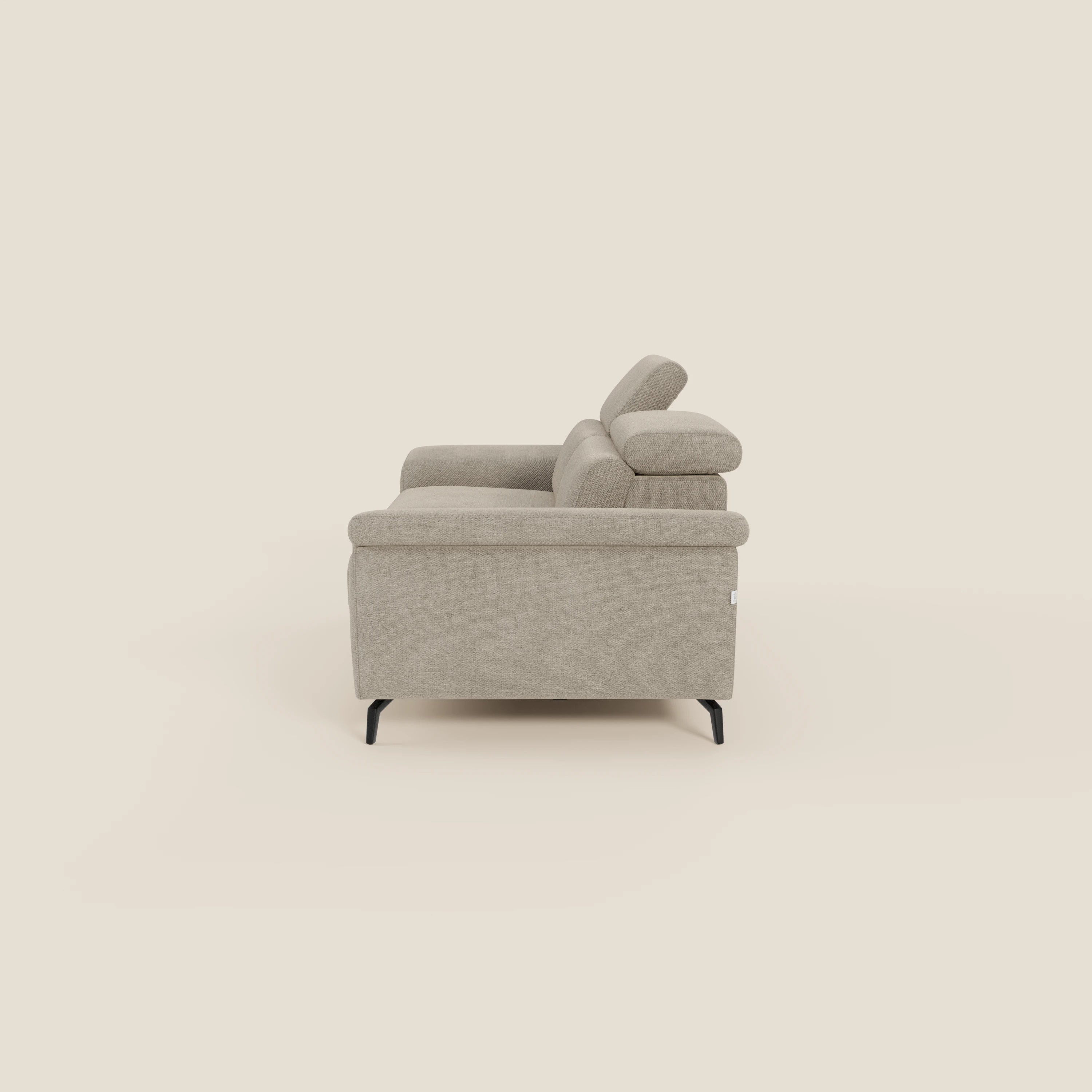 Vista laterale di Estro Divano 3 posti con pouf estraibile di Divani.Store in tessuto beige T14 impermeabile, caratterizzato da poggiatesta reclinabili, gambe corte nere e un design moderno e squadrato su uno sfondo bianco sporco.