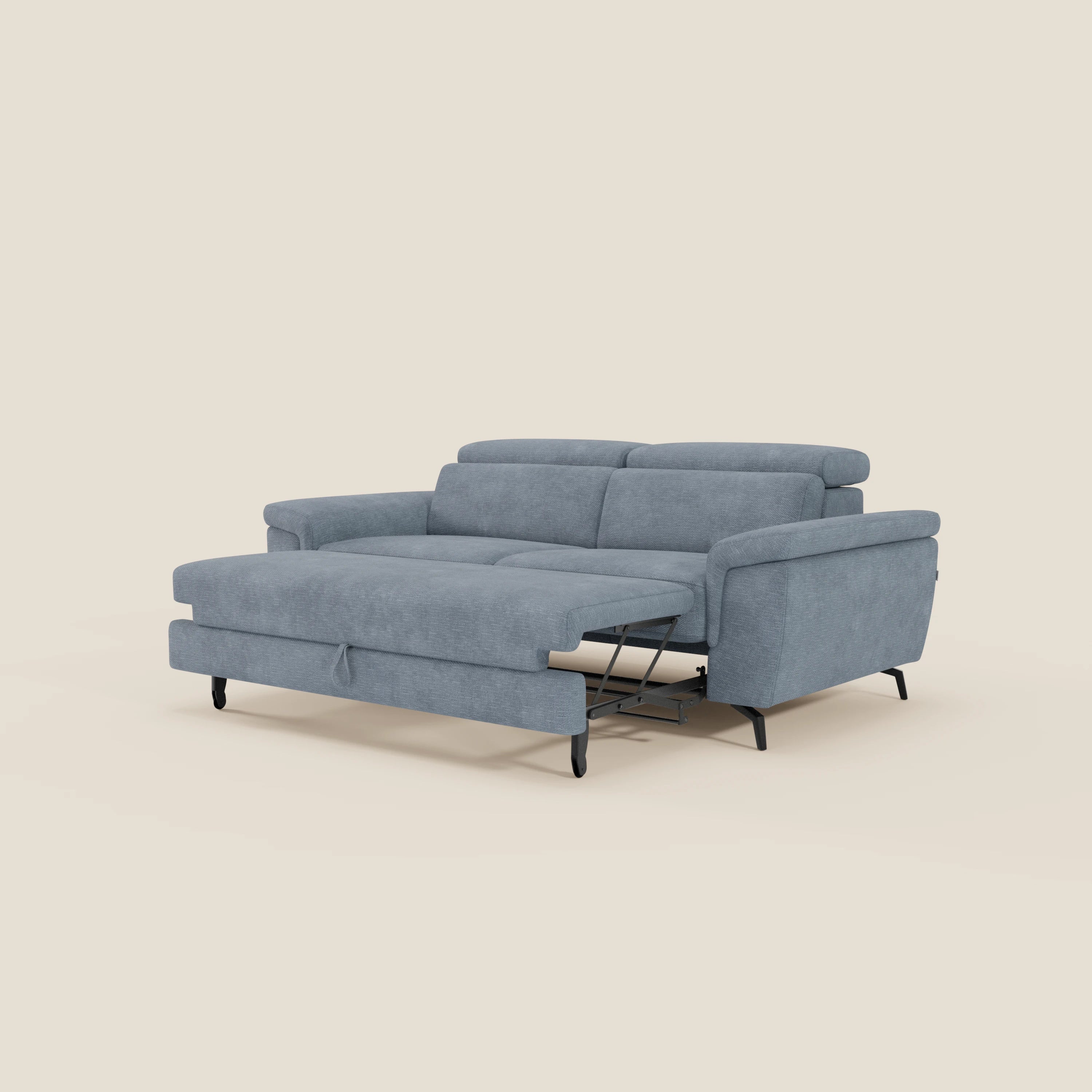 Il divano Estro 3 posti di Divani.Store in tessuto impermeabile T14 carta da zucchero è caratterizzato da poggiatesta regolabili, pouf estraibile, linee pulite, braccioli imbottiti e sottili gambe in metallo nero su un semplice sfondo beige.