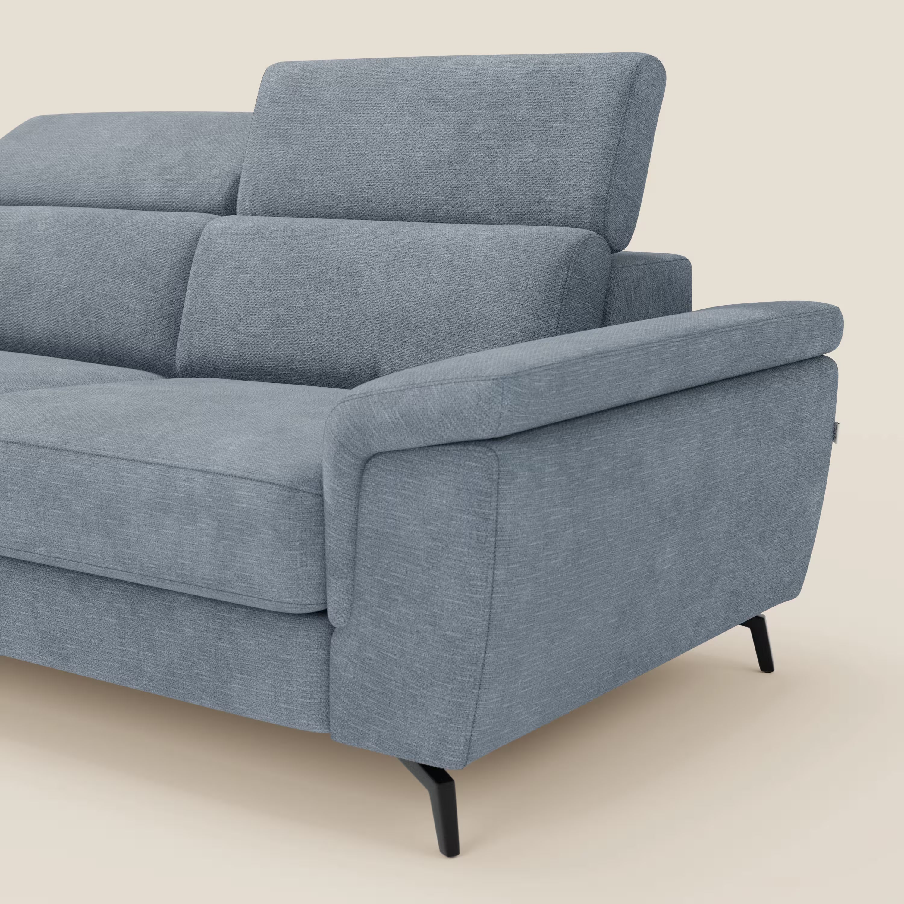 L'Estro Divano 3 posti con pouf estraibile di Divani.Store è caratterizzato da tessuto impermeabile T14 carta da zucchero, poggiatesta reclinabili, ampi braccioli angolati e sottili gambe nere. Mostrato contro uno sfondo beige, lato destro e parte anteriore visibili.