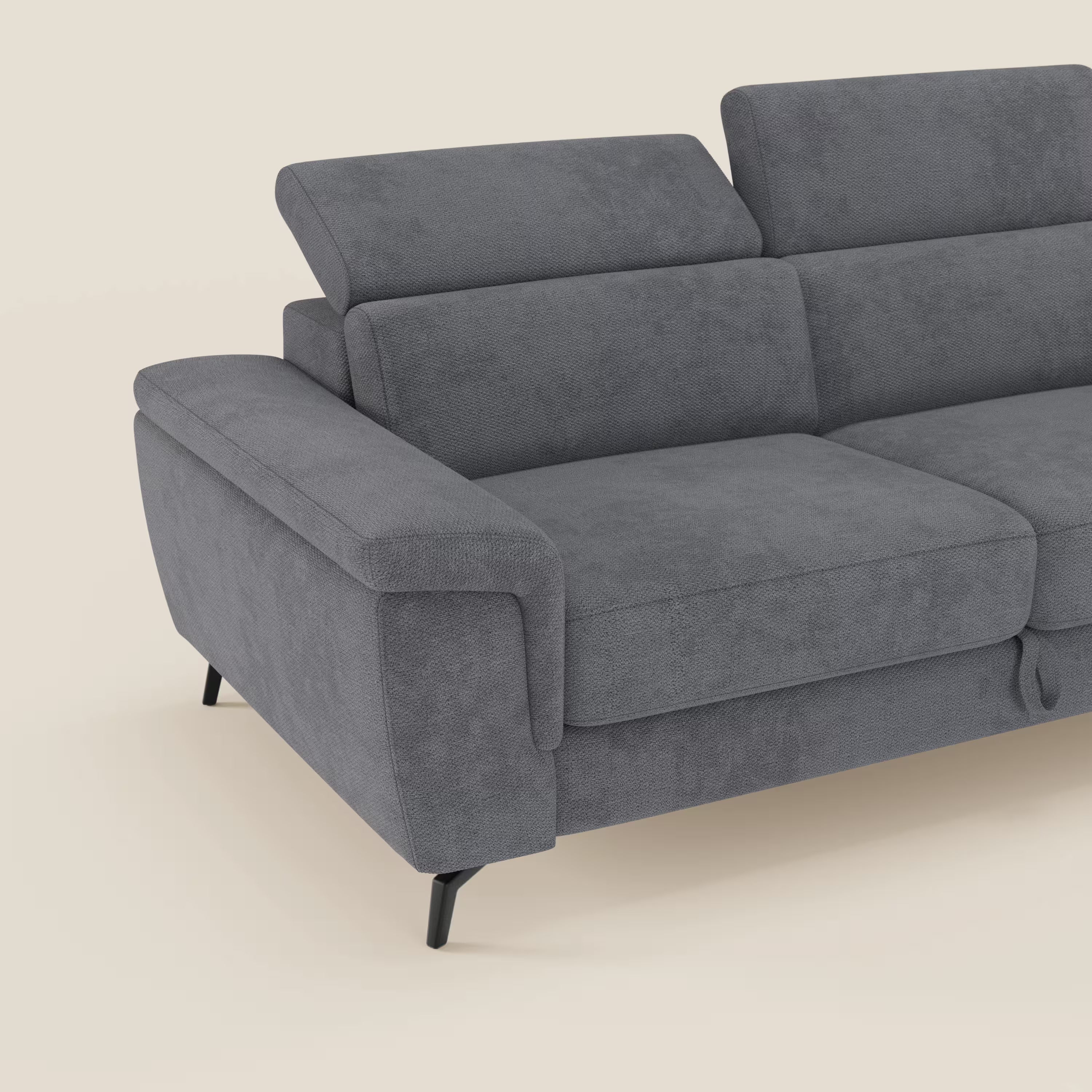 L'Estro Divano 3 posti con pouf estraibile di Divani.Store, in tessuto impermeabile T14 grigio con poggiatesta reclinabili, è mostrato parzialmente su uno sfondo beige chiaro. È visibile solo una parte del divano moderno grigio.