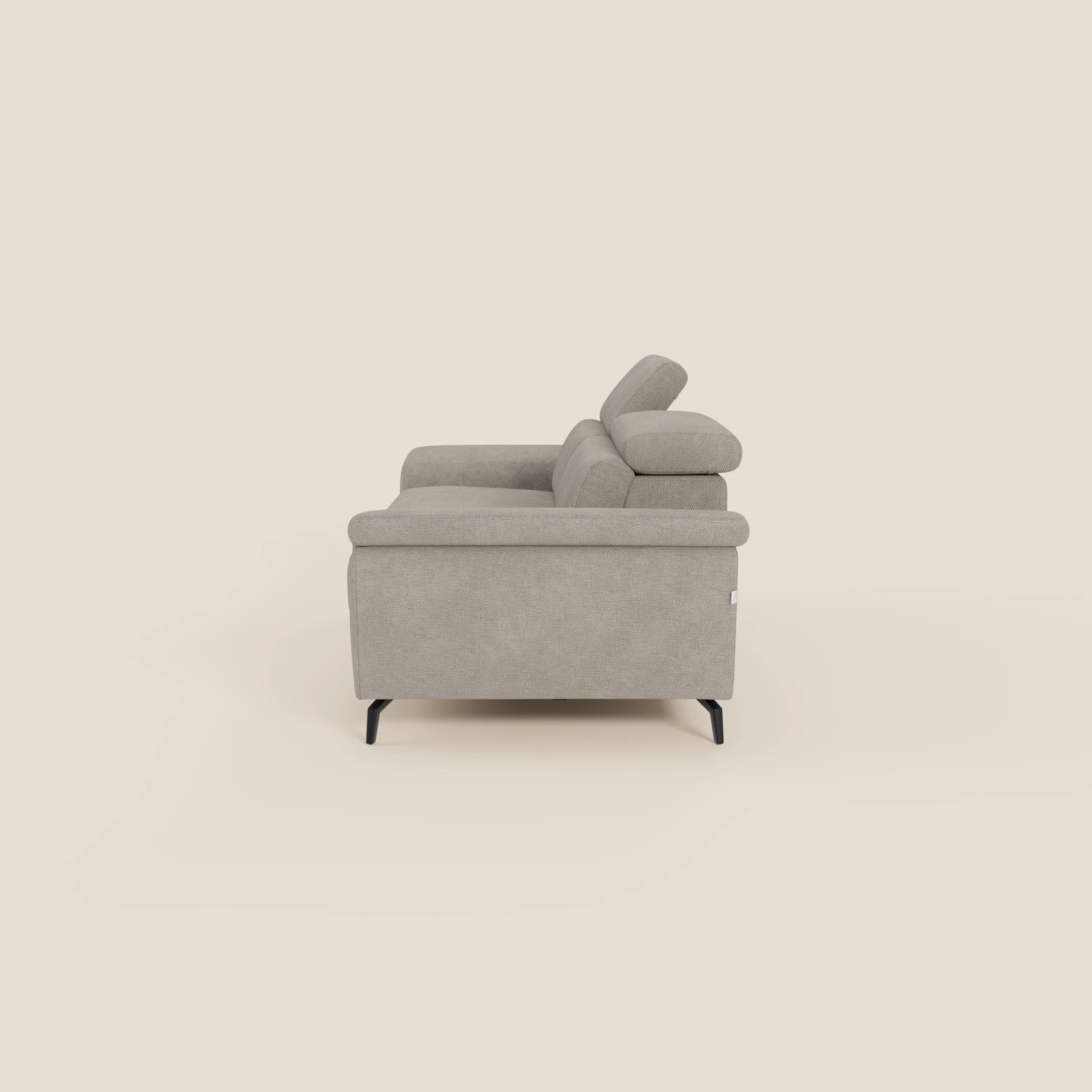 Estro Divano 3 posti con pouf estraibile di Divani.Store è presentato lateralmente su sfondo beige, con poggiatesta reclinabili, gambe sottili nere e tessuto impermeabile T14 tortora per una facile manutenzione in uno stile elegante e minimalista.
