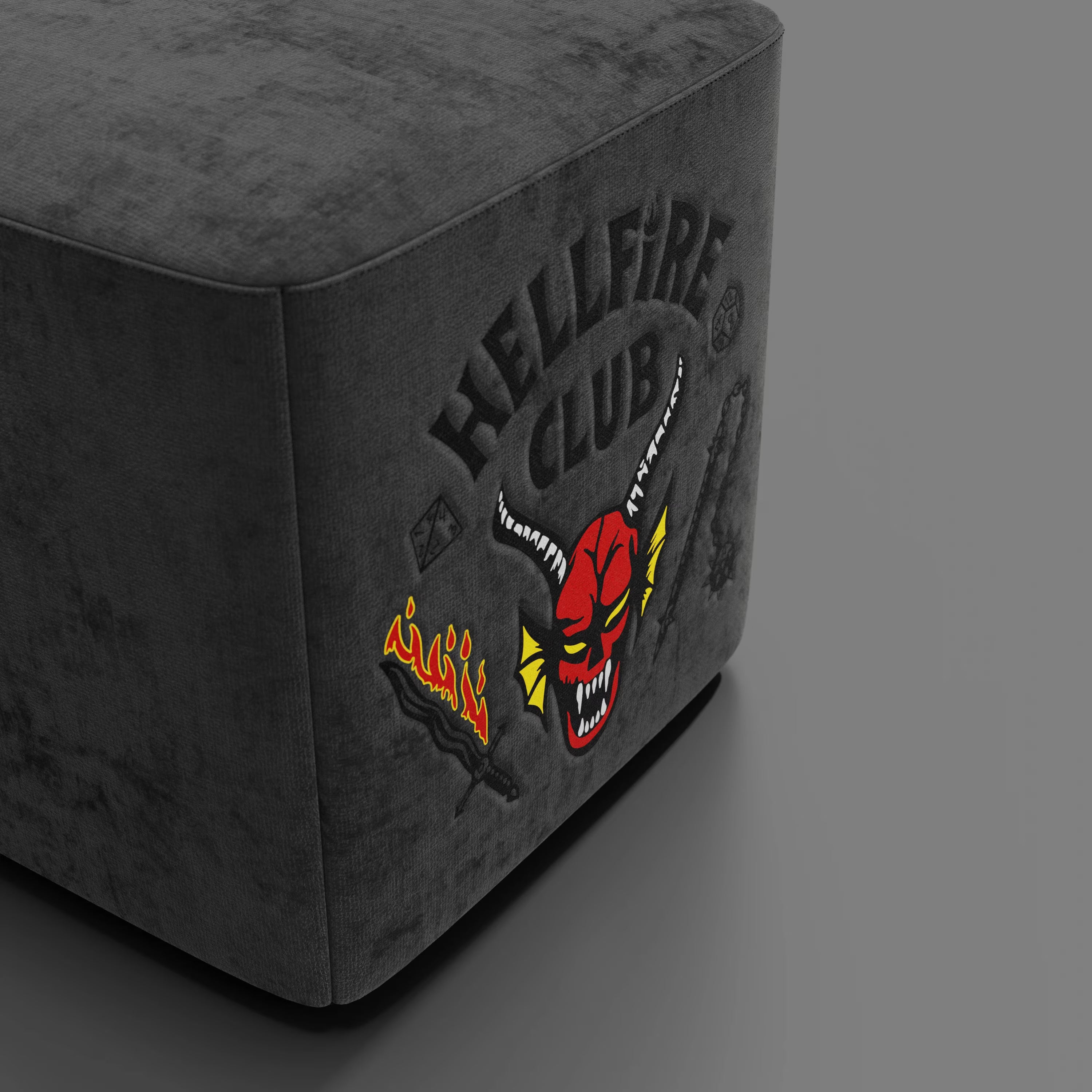 Il pouf Cube Hellfire club Stranger Things Edition di Divani.Store è caratterizzato da un design antracite con ricami vivaci del logo "HELLFIRE CLUB", testa di diavolo rossa, toppe infuocate, armi e dadi. Edizione limitata per i fan.