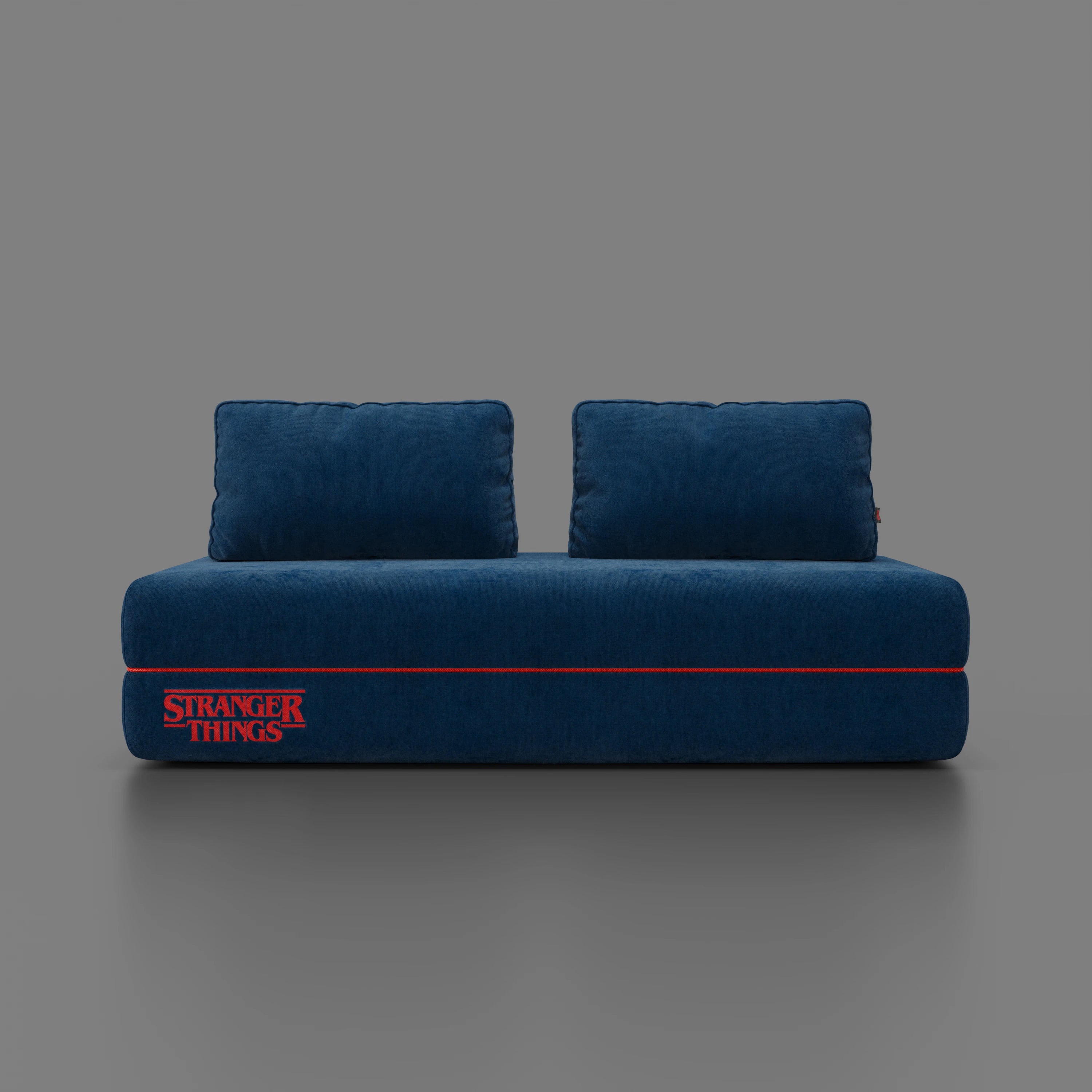 Il divano letto matrimoniale Rift STRANGER THINGS Edition di Divani.Store, in tessuto blu smacchiabile con schienali sfoderabili e logo "Stranger Things" in rosso, ha un materasso in memory foam da 22 cm e può ospitare due o tre persone.