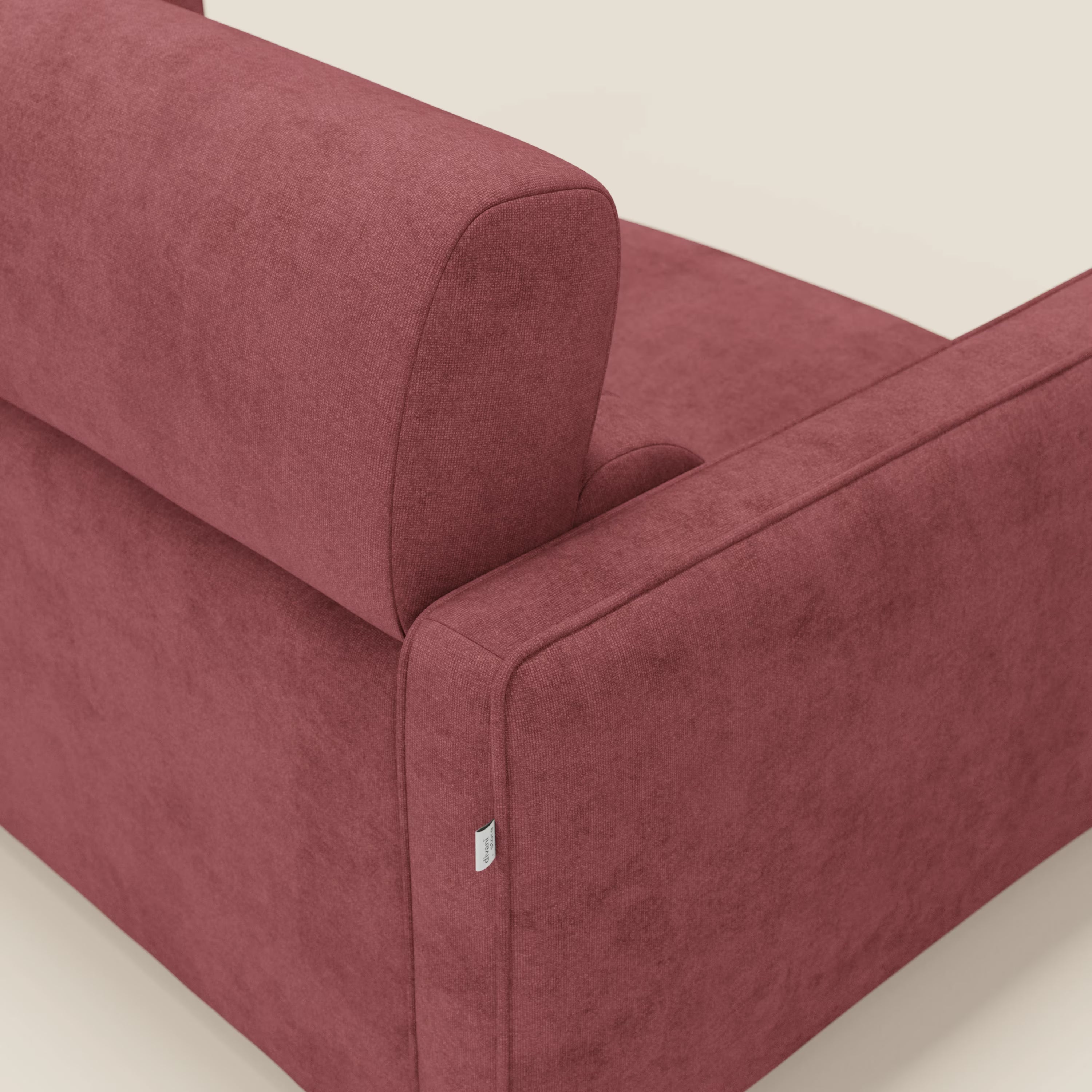 Un primo piano del Nivon Divano letto moderno di Divani.Store mostra il suo morbido tessuto impermeabile rosso T25, la consistenza felpata, le linee pulite e il design italiano con una piccola etichetta sulla cucitura del bracciolo. Include materasso H16 cm e poggiatesta regolabile.