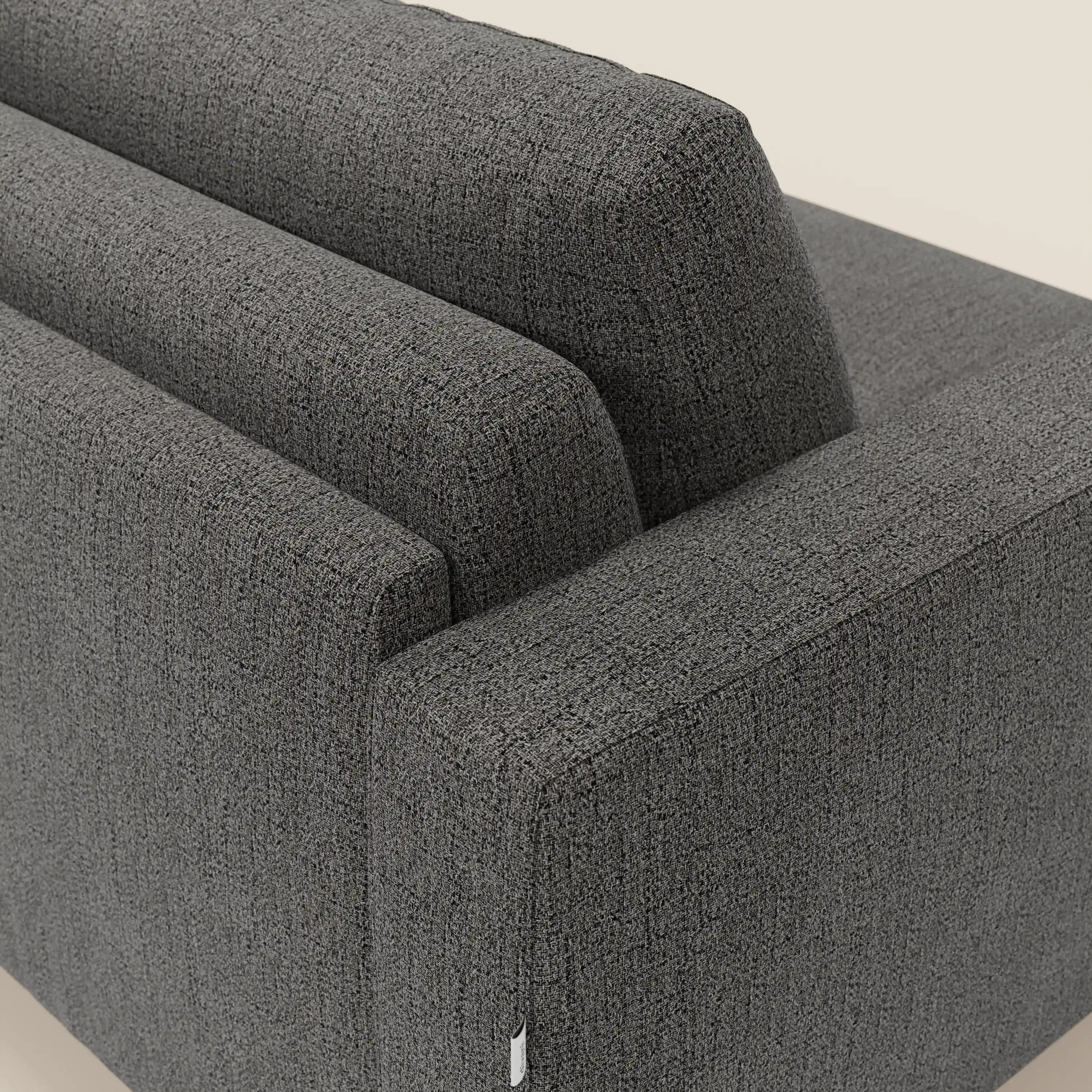 Un primo piano del letto matrimoniale Alaya Divano di Divani.Store in tessuto impermeabile T03 antracite mette in mostra i suoi morbidi cuscini, l'imbottitura strutturata e le linee decise su uno sfondo chiaro.