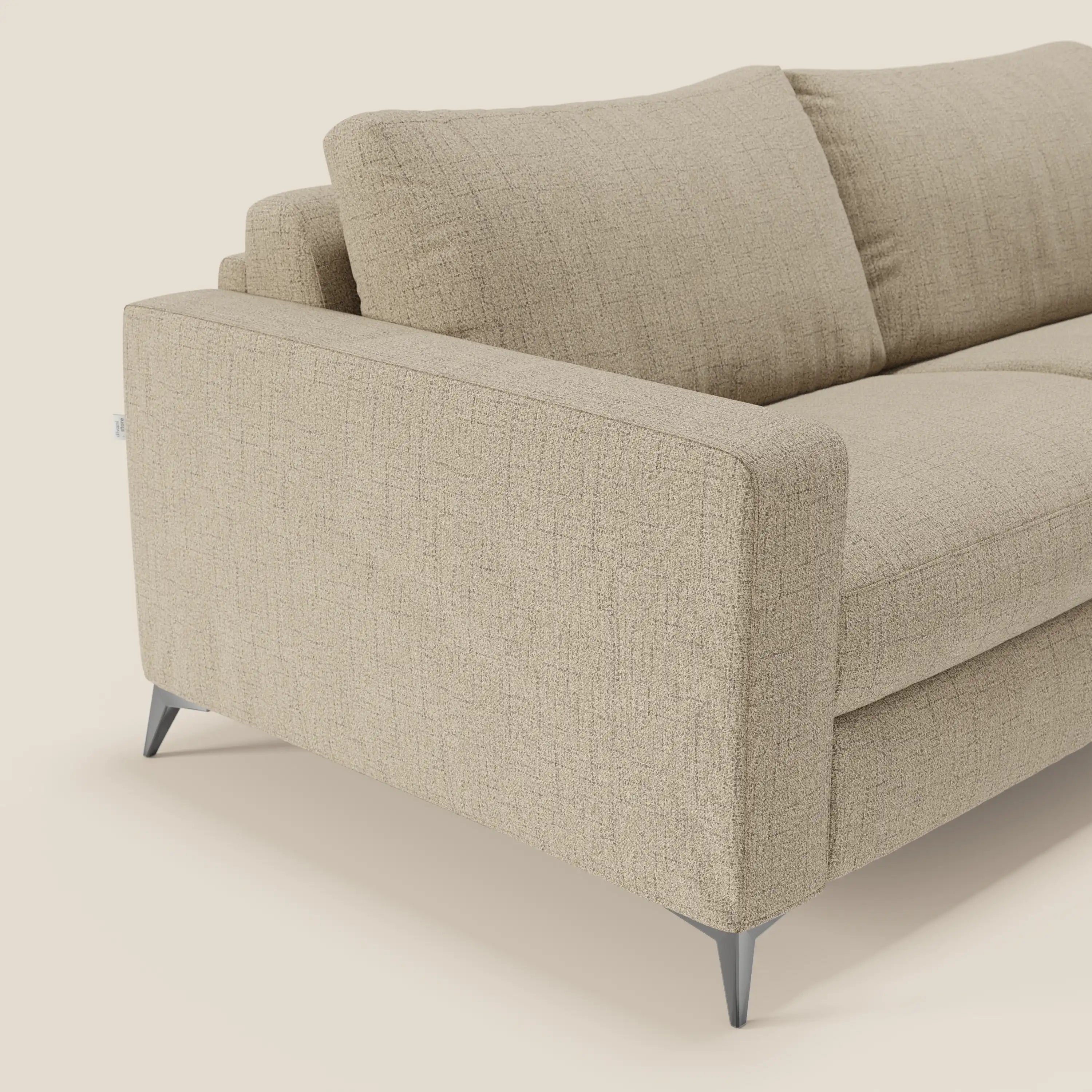 Un primo piano del divano letto matrimoniale Alaya di Divani.Store in impermeabile T03 beige mostra l'imbottitura testurizzata, i braccioli quadrati, le gambe metalliche angolate e i cuscini in tessuto, che evidenziano il suo stile pulito e contemporaneo.