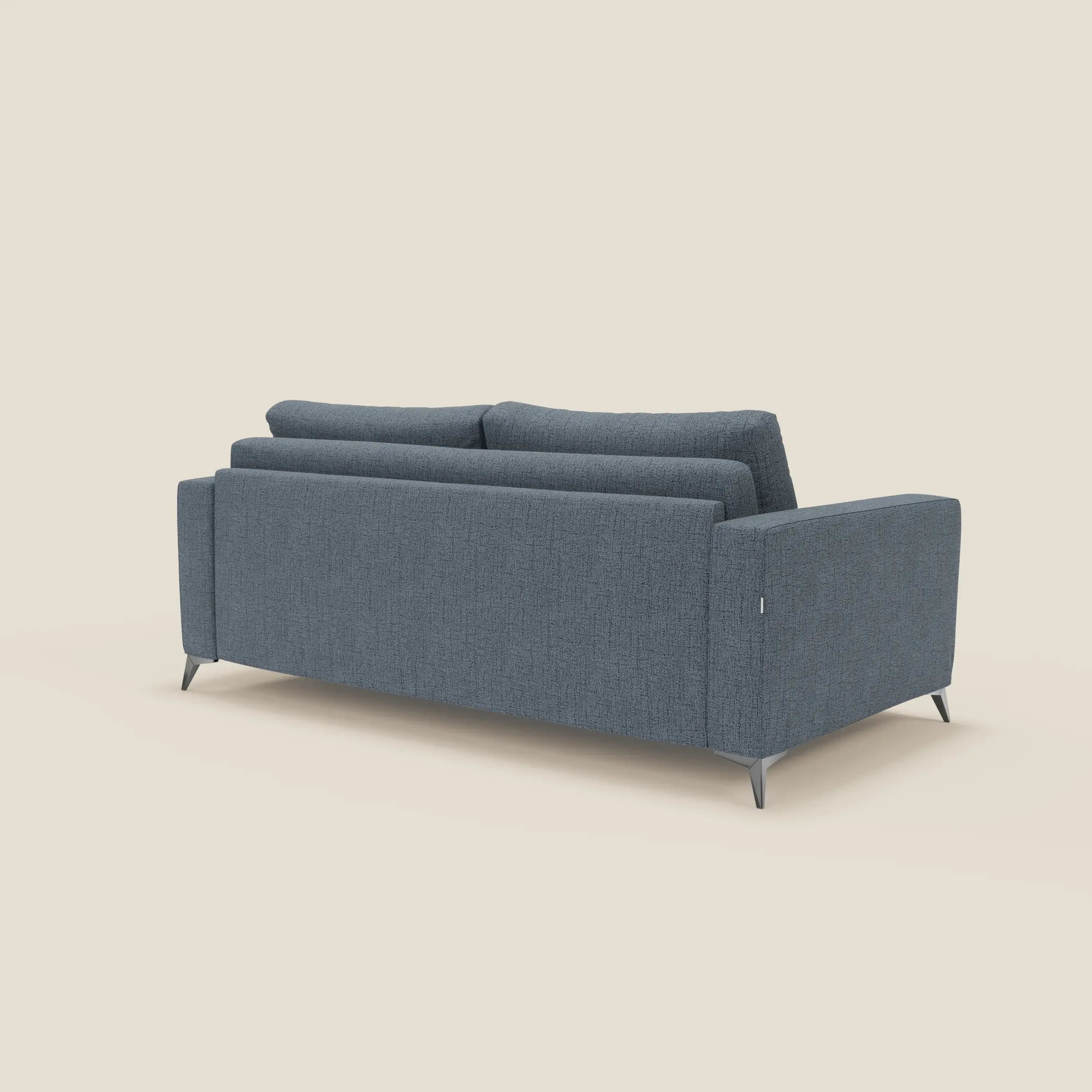 Il letto matrimoniale Alaya Divano di Divani.Store è presentato da dietro in posizione angolata, in tessuto impermeabile T03 blu con gambe in metallo, stile minimale, linee rette, profilo basso e due morbidi cuscini per lo schienale su sfondo beige.