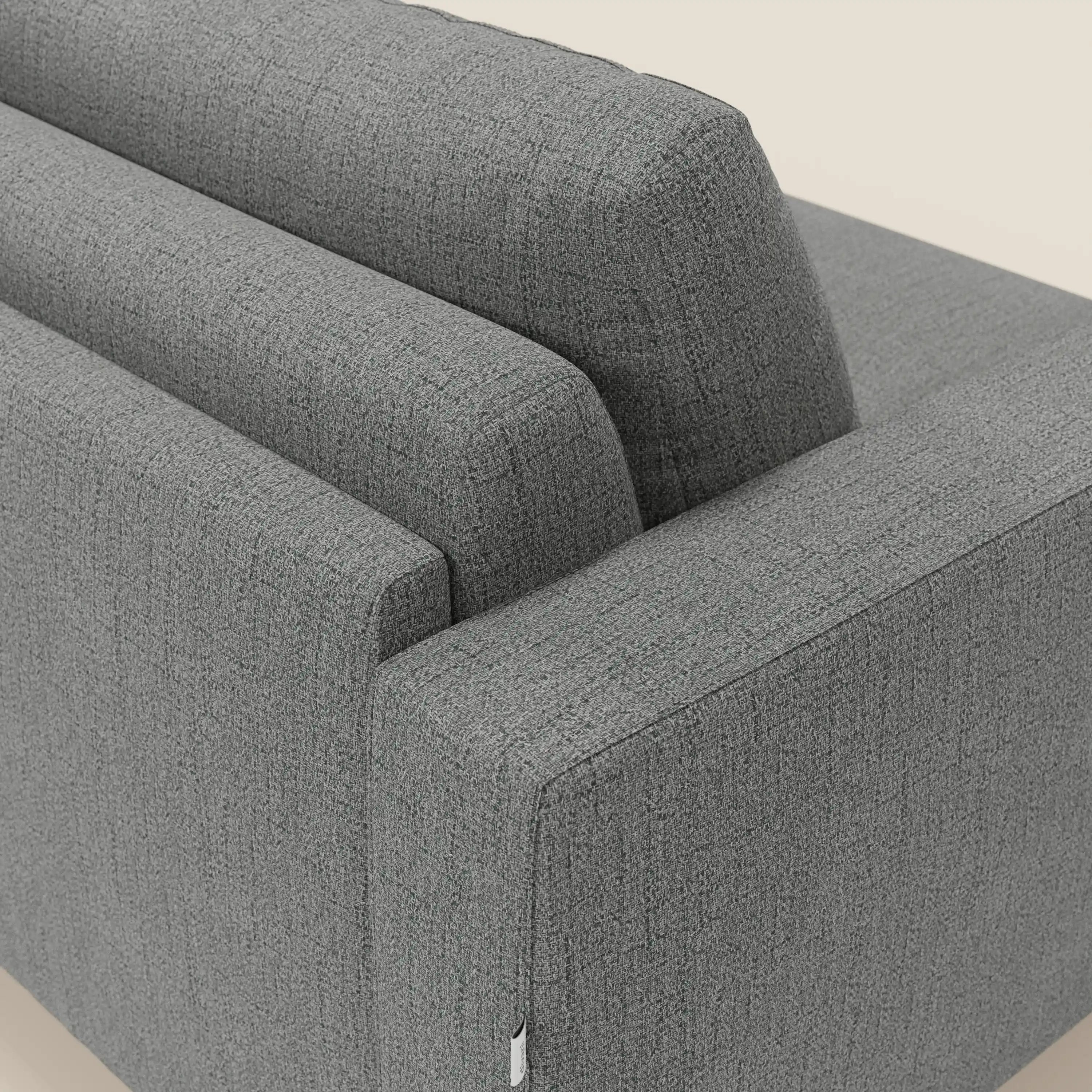 Primo piano del letto matrimoniale Alaya Divano di Divani.Store in impermeabile T03 grigio, che mostra le sue linee pulite, il bracciolo rettangolare e l'intreccio strutturato per un look minimal su uno sfondo beige chiaro.