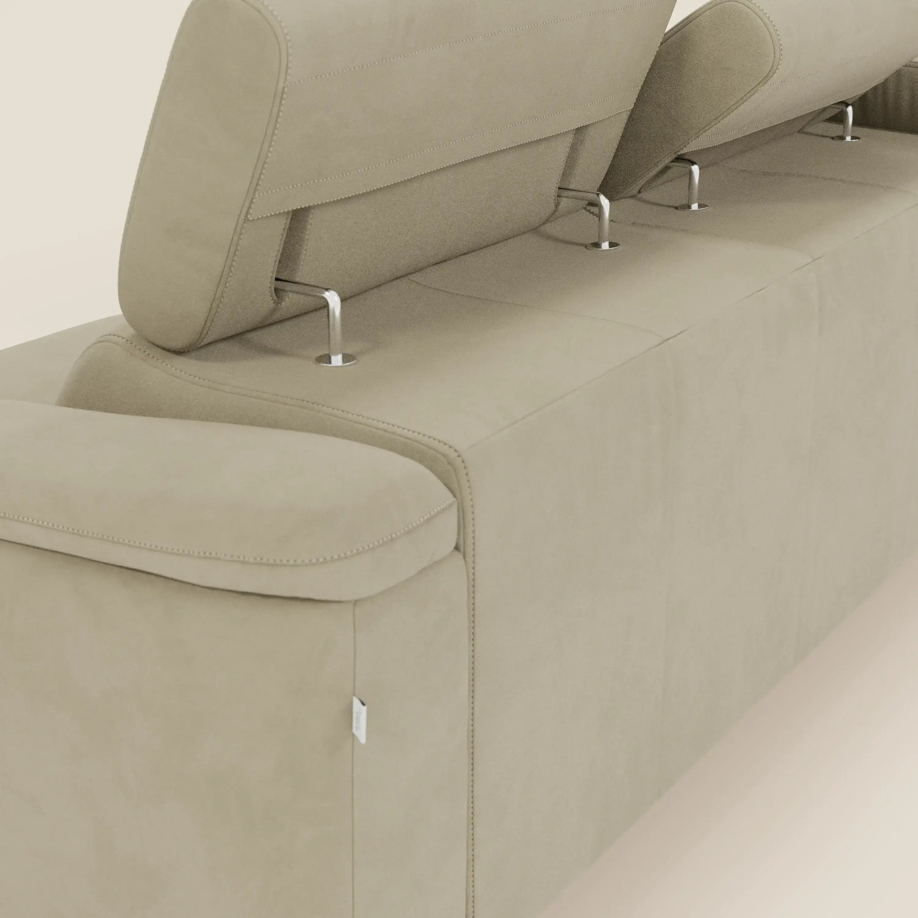 Un primo piano dell'Arcos Divano con penisola di Divani.Store mostra la microfibra impermeabile beige T11, i due poggiatesta reclinabili con supporti in metallo, le cuciture lisce, l'etichetta laterale in tessuto e i piedini alti, su uno sfondo chiaro.