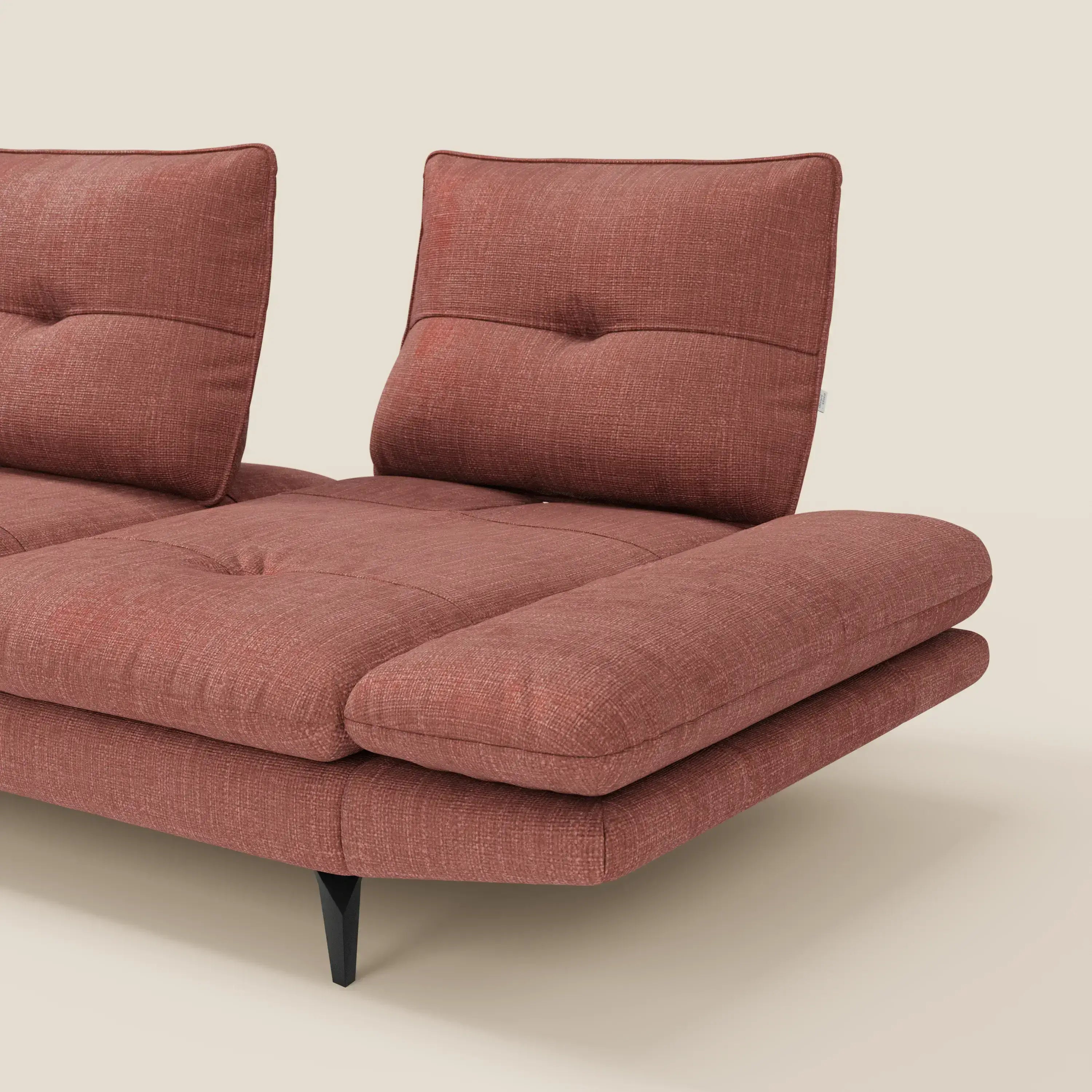 L'Ardex Divano con penisola di Divani.Store, presentato in elegante tessuto impermeabile T06 corallo con schienali scorrevoli e braccioli regolabili, è caratterizzato da spesse sedute imbottite e sottili gambe nere. Su uno sfondo beige chiaro, è visibile solo una parte.