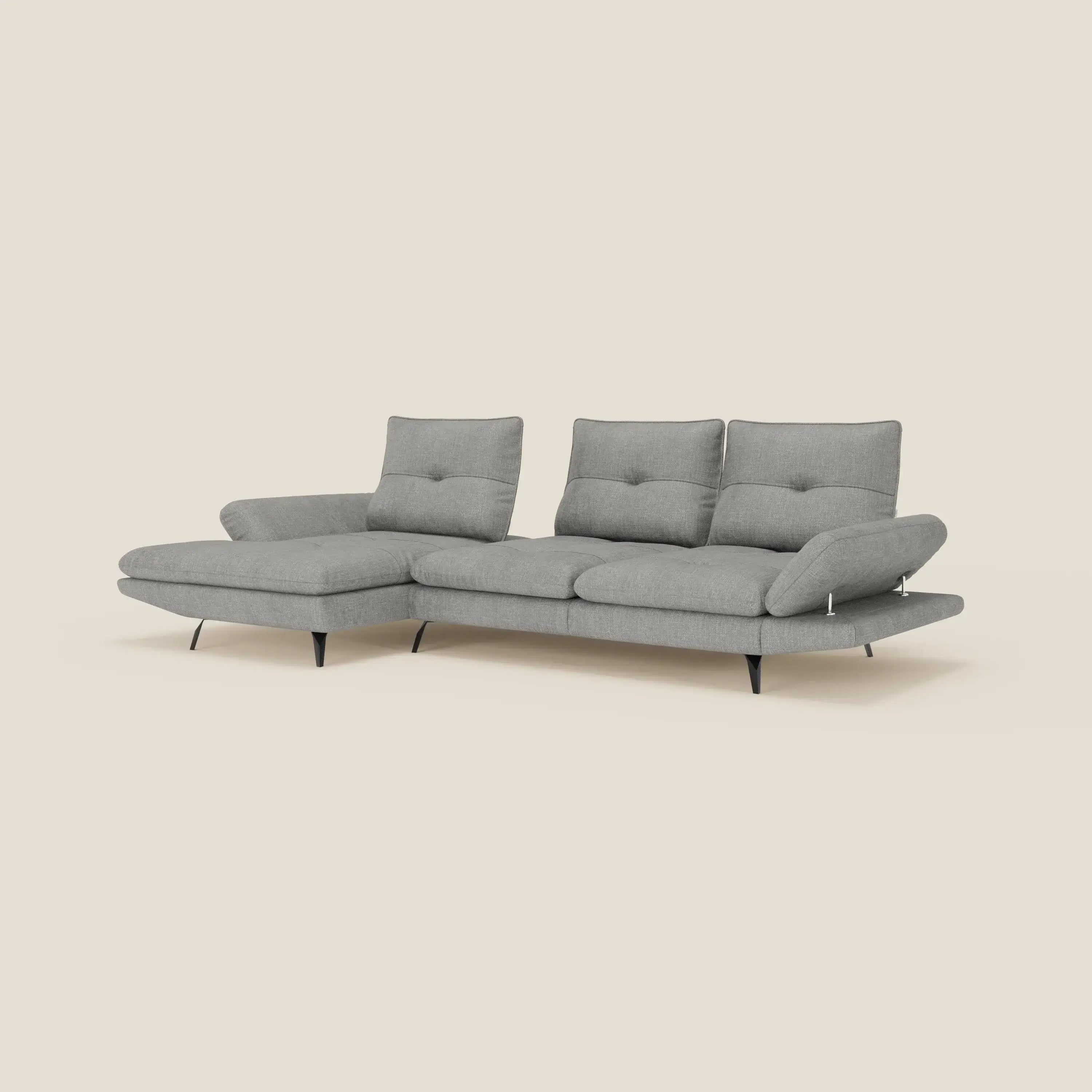 Ardex Divano con penisola di Divani.Store è un moderno divano angolare grigio in tessuto impermeabile T06, caratterizzato da tre schienali scorrevoli, braccioli regolabili, dettagli trapuntati, sottili gambe nere e una chaise allungabile a L.