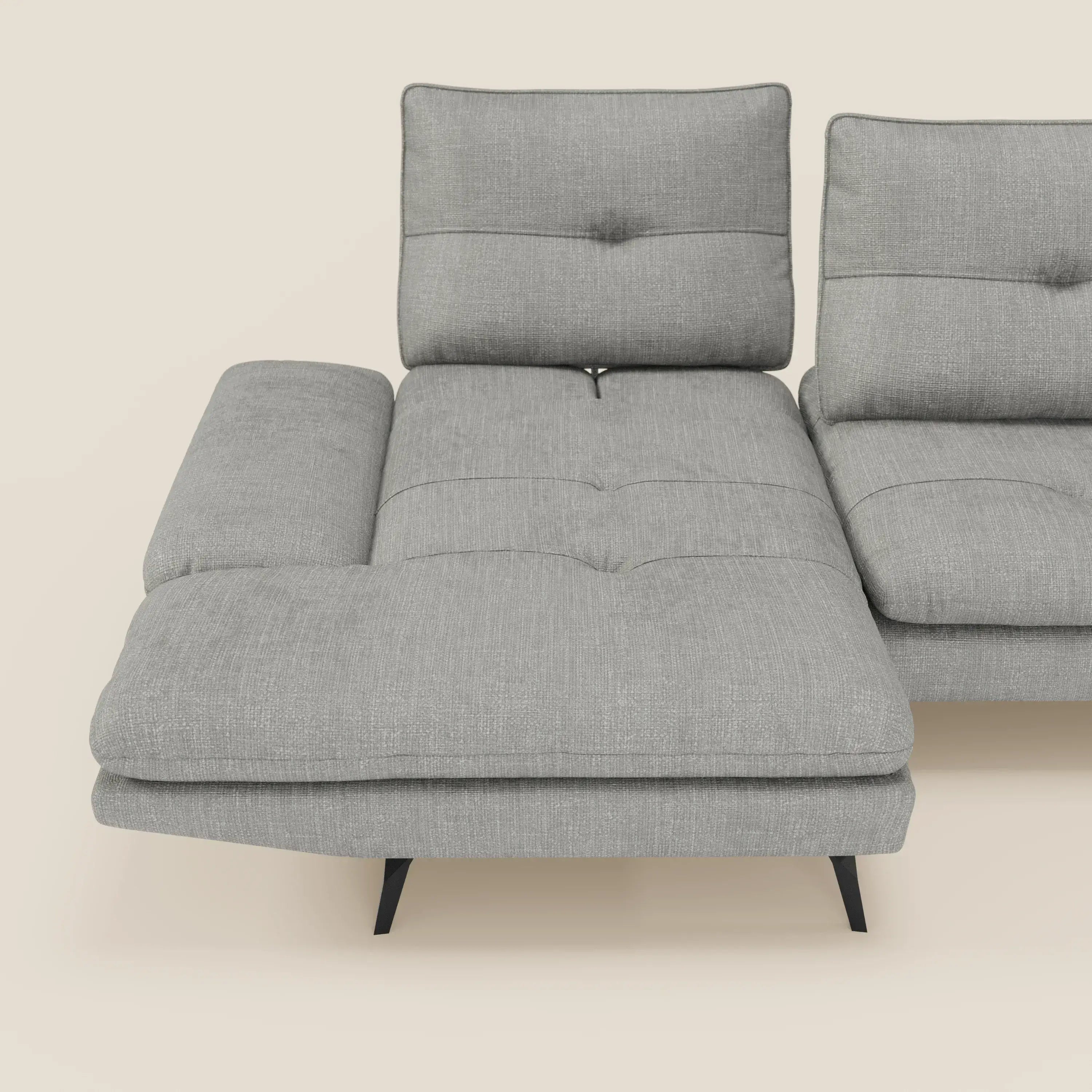 Ardex Divano con penisola di Divani.Store è presentato in tessuto impermeabile grigio T06 con schienali scorrevoli, braccioli regolabili, cuscini trapuntati e gambe angolari nere. La sezione di sinistra è dotata di una chaise longue; lo sfondo è in bianco sporco.