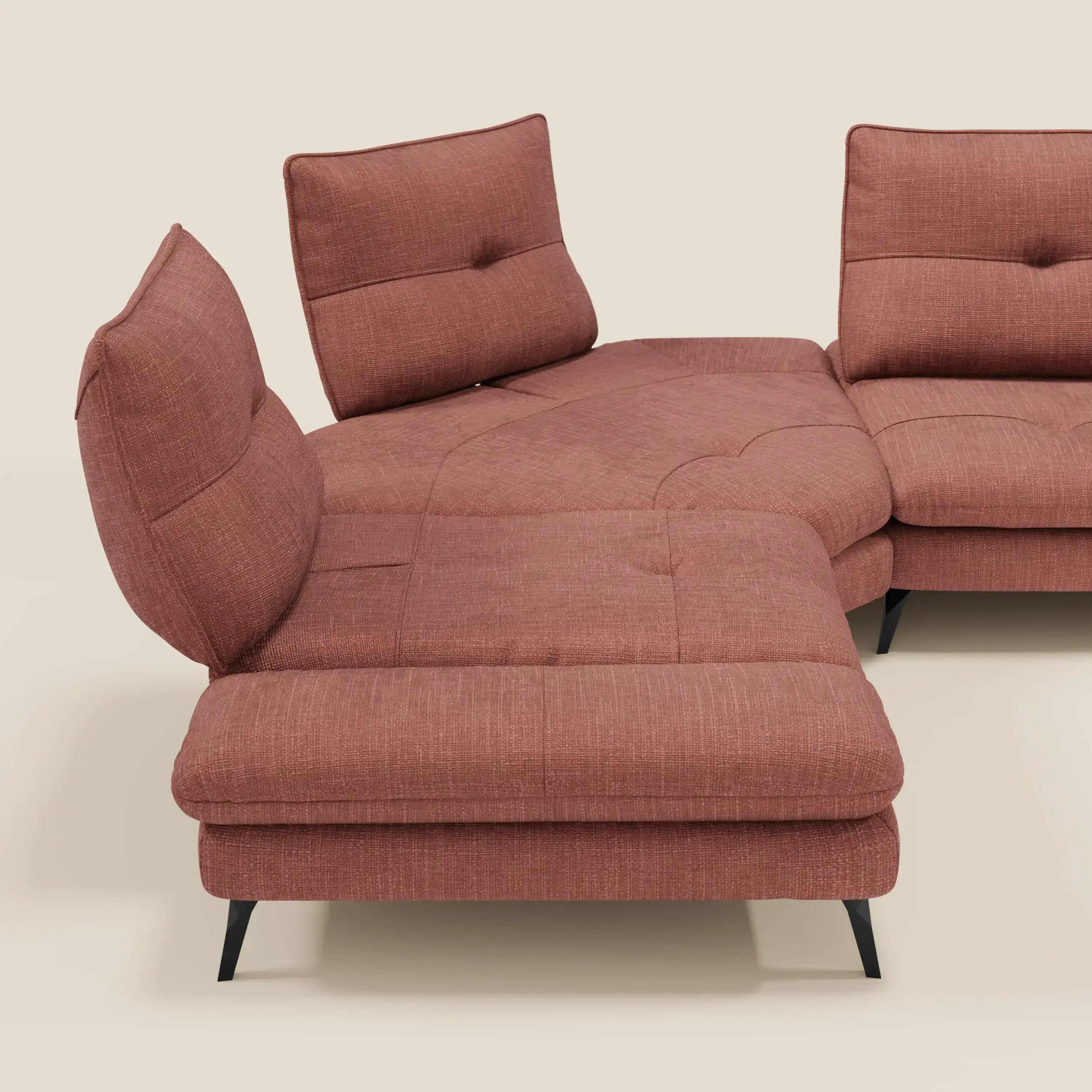 Ardex Divano Angolare di Divani.Store è caratterizzato da schienali traslanti, bracciolo regolabile ed elegante tessuto impermeabile T06 corallo. Questo moderno divano a L poggia su sottili gambe nere su uno sfondo beige chiaro.