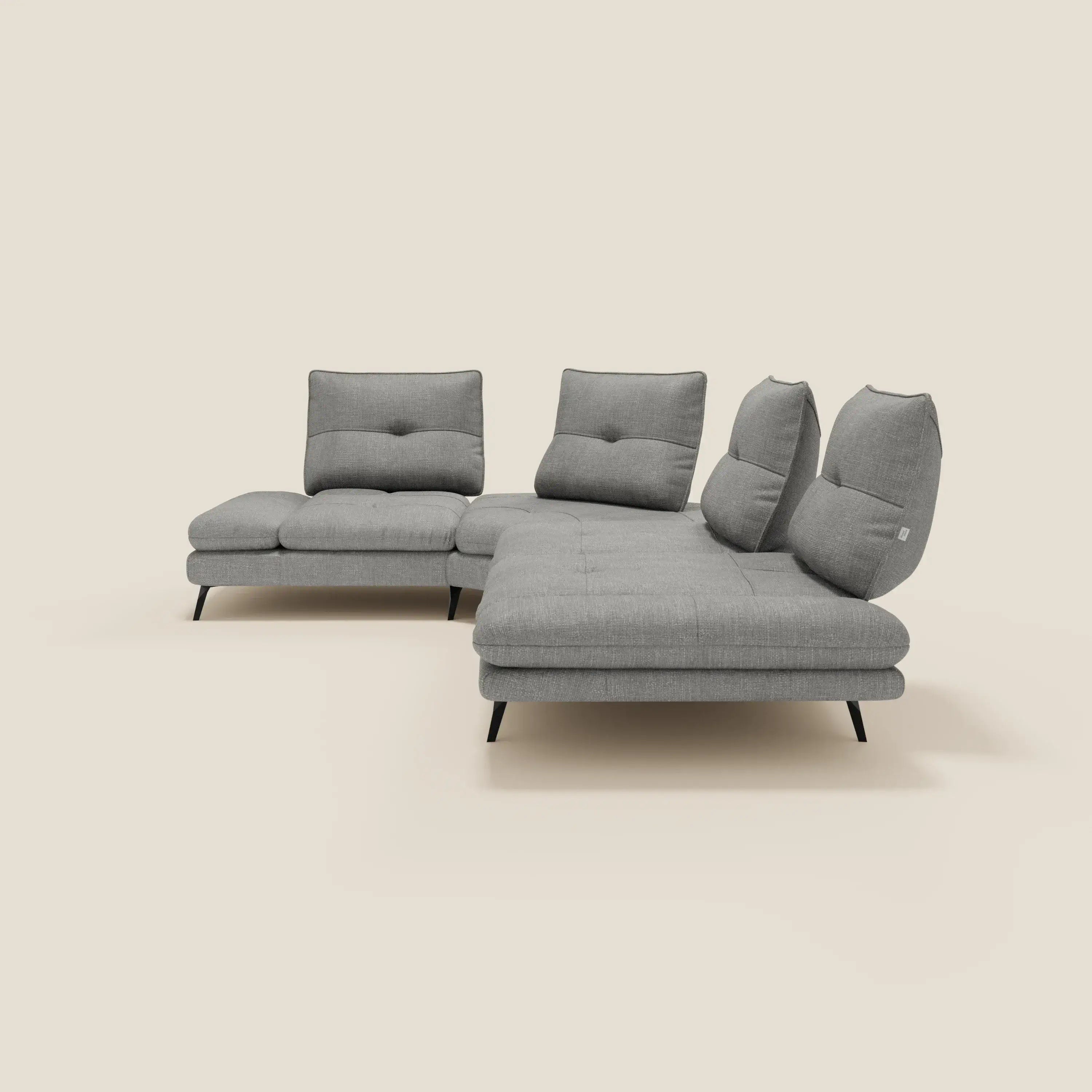 Ardex Divano Angolare di Divani.Store è caratterizzato da schienali traslanti, bracciolo regolabile ed elegante tessuto impermeabile T06 grigio. Il suo design moderno con cuscini trapuntati poggia su gambe angolari nere su uno sfondo color crema.