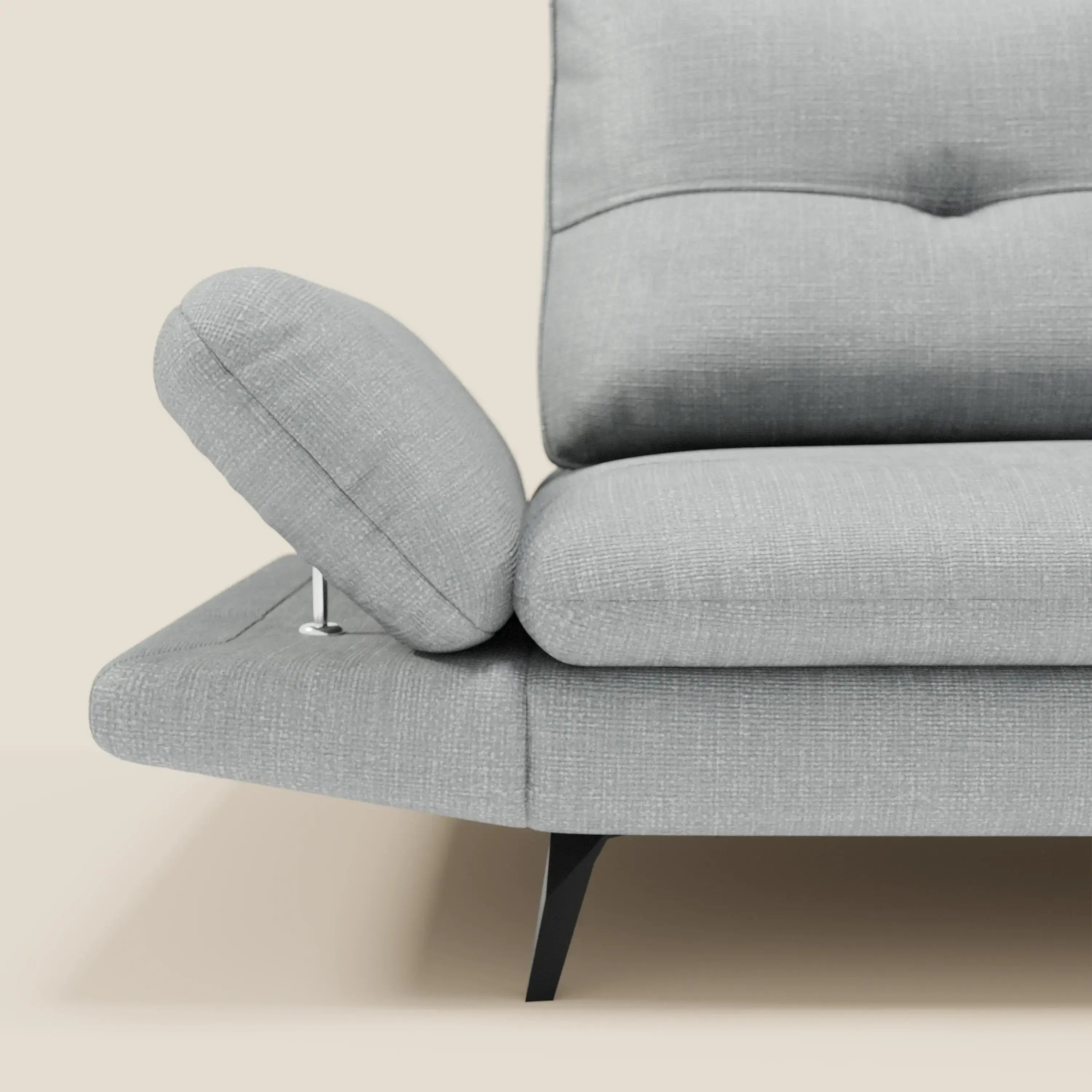 Primo piano di Ardex Divano 3 posti di Divani.Store in morbido tessuto impermeabile T06 ghiaccio con braccioli regolabili, cuscini trapuntati e gambe nere angolate, su sfondo beige con un lato visibile.