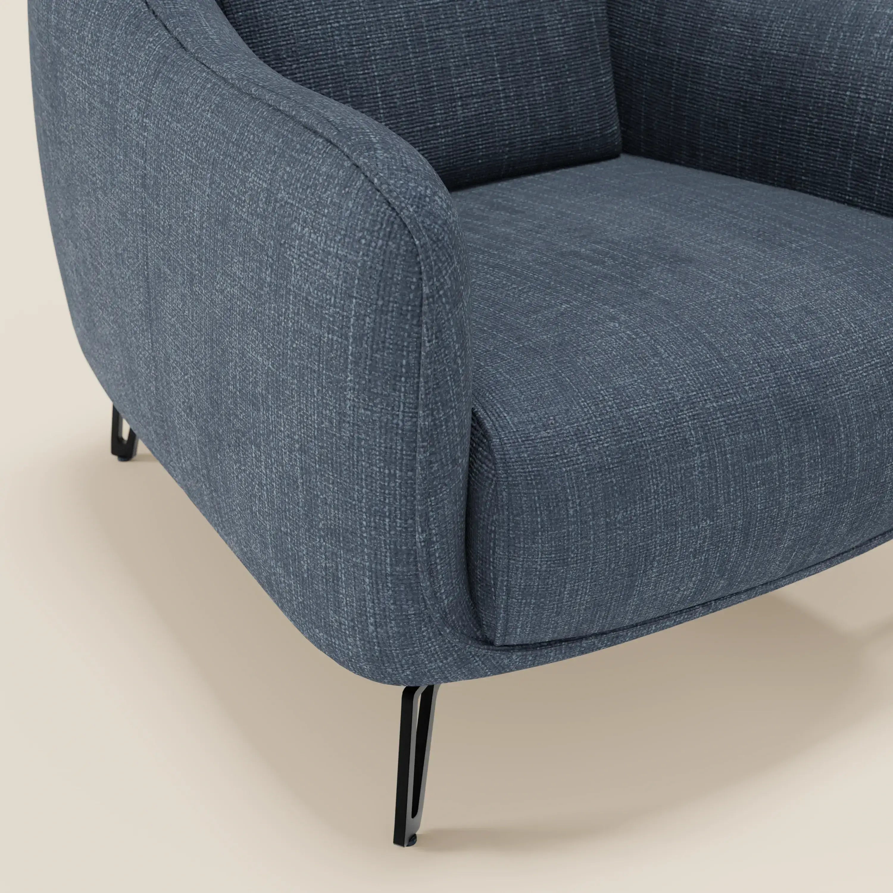Primo piano di Avela Poltroncina di Divani.Store in morbido tessuto impermeabile blu T06, che mette in evidenza il bracciolo curvo, la seduta, lo schienale e le eleganti gambe in metallo nero su uno sfondo beige neutro.