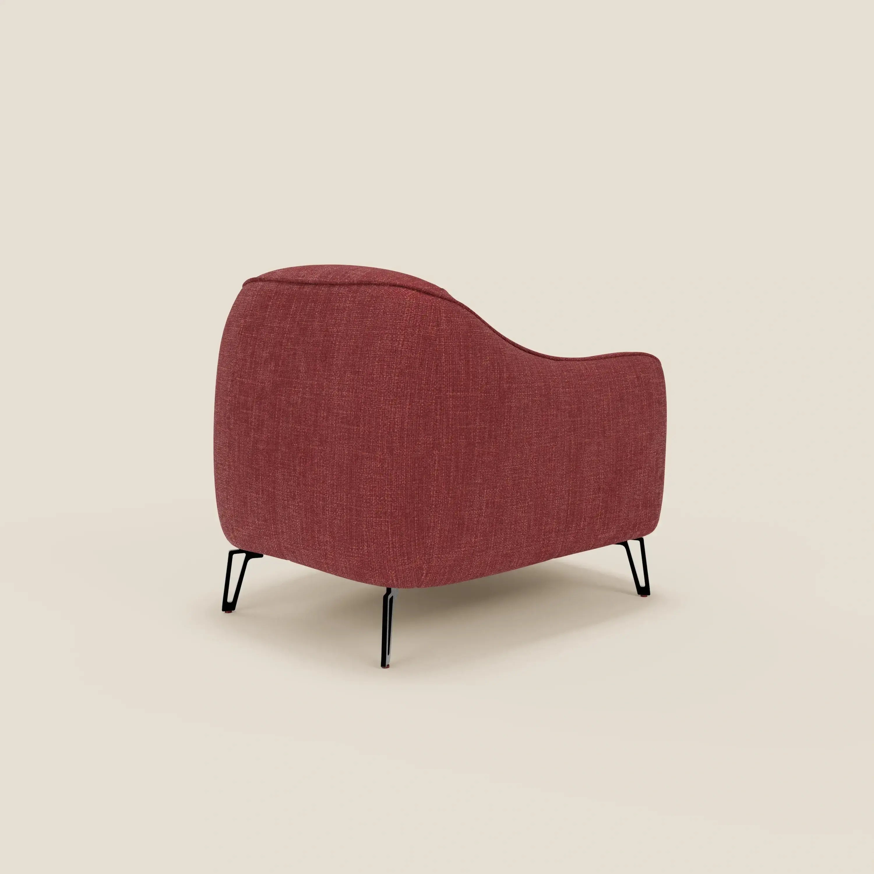 La poltroncina Avela di Divani.Store, in morbido tessuto impermeabile T06 rosso, presenta linee curve e sottili gambe in metallo nero. Lo schienale e i braccioli continui creano una silhouette moderna su uno sfondo beige chiaro.