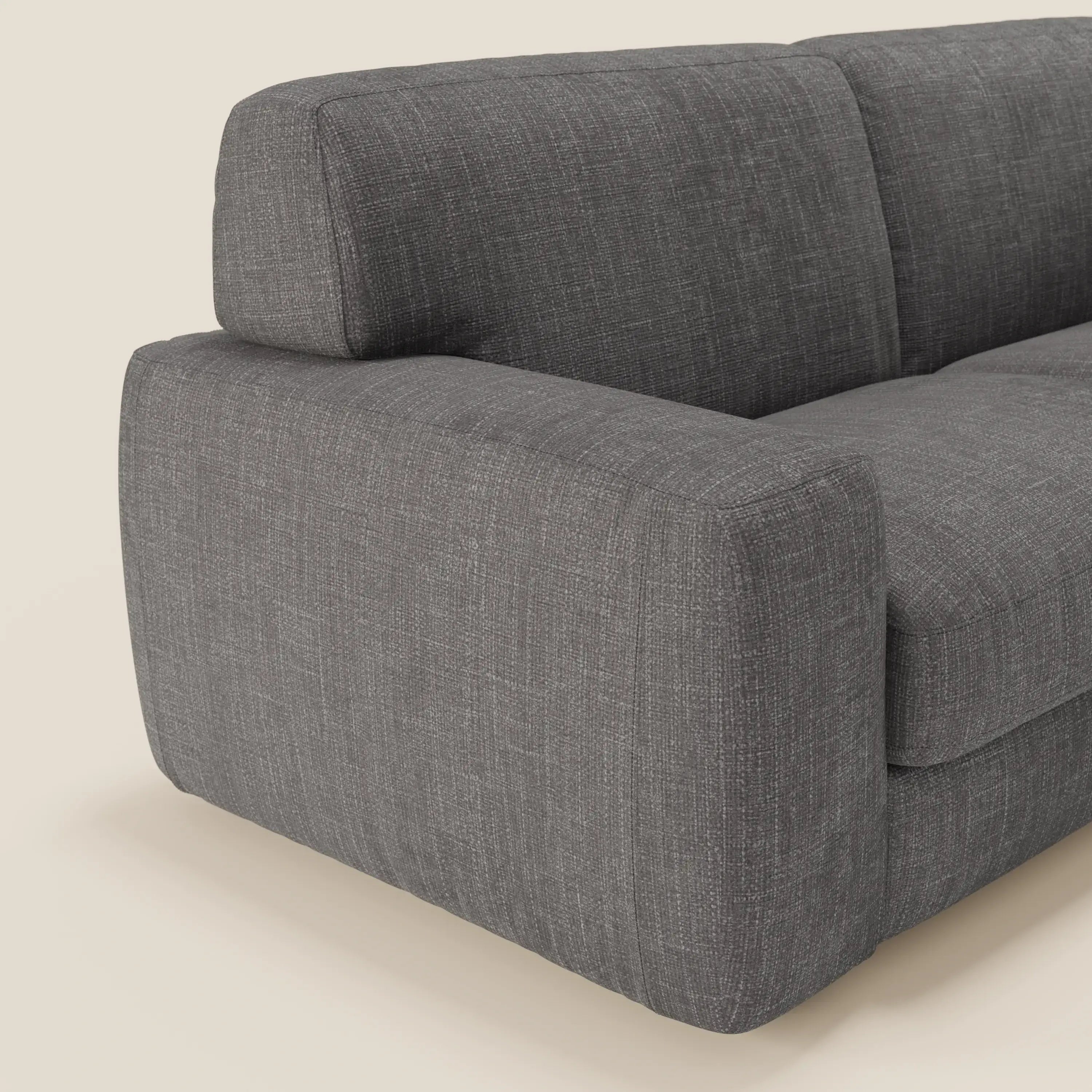 Primo piano del letto materasso Cloud Divano H17 cm di Divani.Store, in tessuto impermeabile T06 antracite. L'immagine evidenzia il bracciolo sinistro, la seduta e il cuscino dello schienale dalle linee pulite e dall'aspetto felpato su uno sfondo beige.