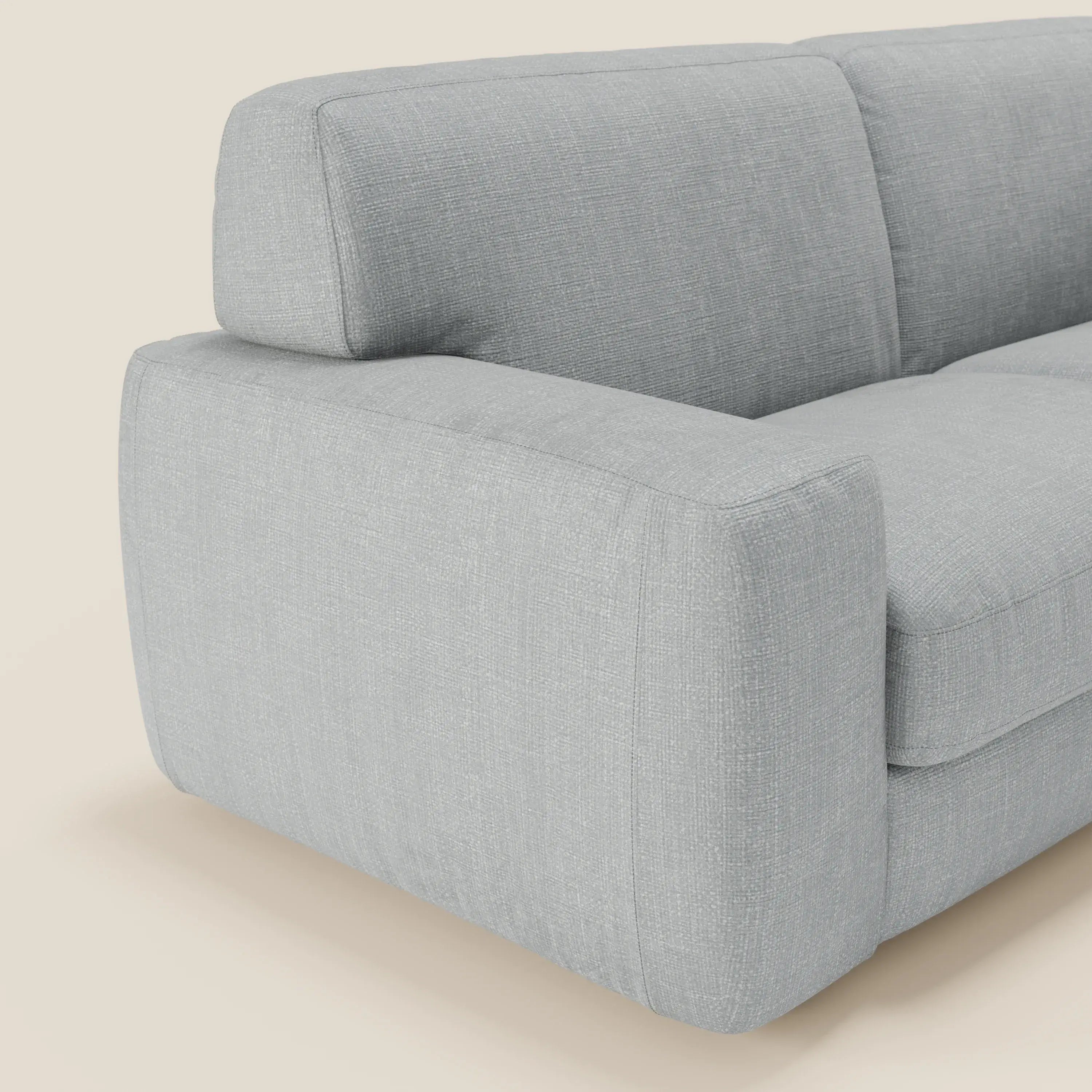 Il divano letto materasso Cloud H17 cm di Divani.Store è caratterizzato da morbidi cuscini in tessuto impermeabile T06 ghiaccio e da un design squadrato e minimalista. Presentato in primo piano su uno sfondo beige chiaro, il suo rivestimento grigio chiaro è morbido e leggermente strutturato.