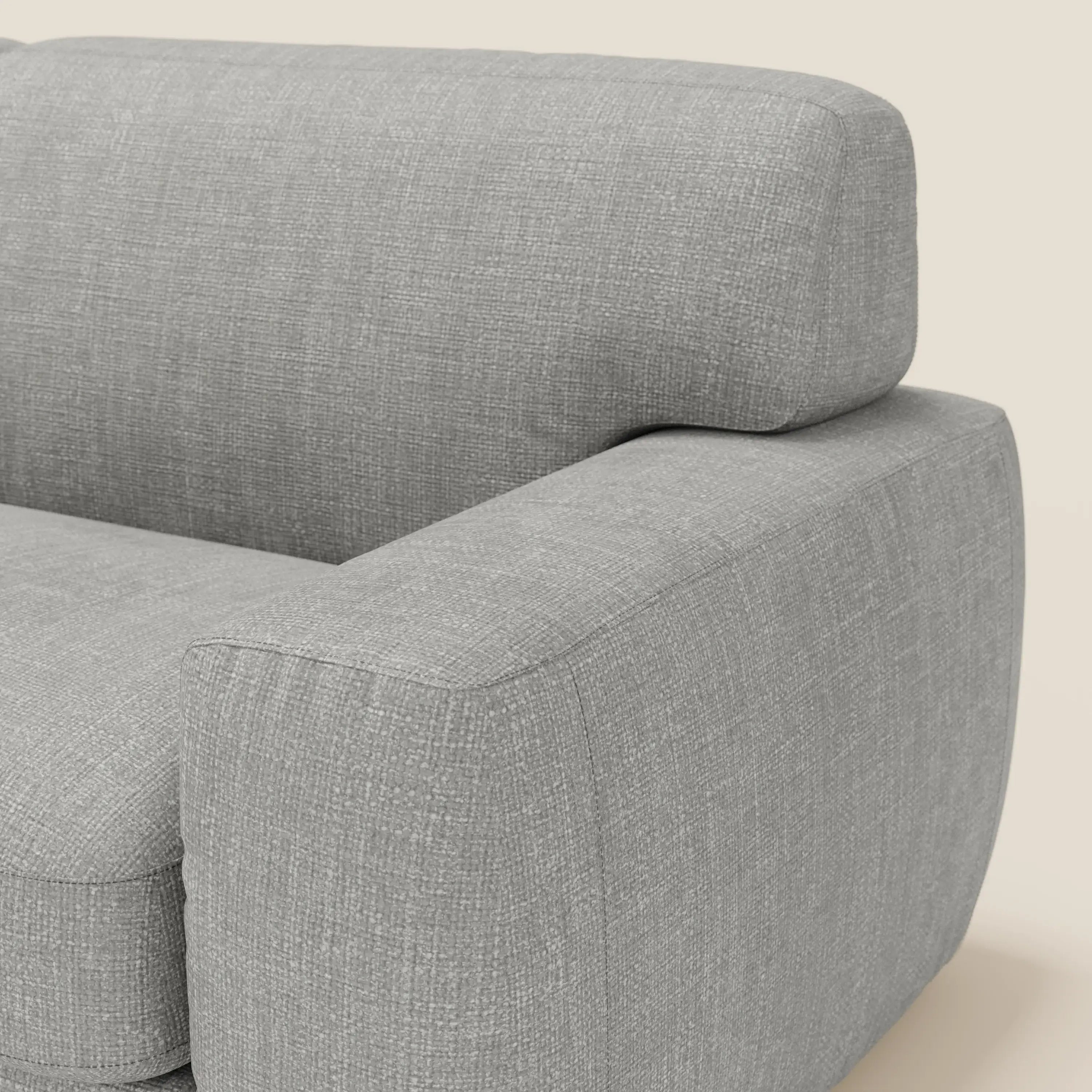 Primo piano del letto materasso Cloud Divano H17 cm di Divani.Store, caratterizzato da morbidi cuscini in tessuto impermeabile grigio T06, ampi braccioli in tessuto felpato e uno spesso schienale dalle linee pulite su un leggero sfondo bianco sporco.