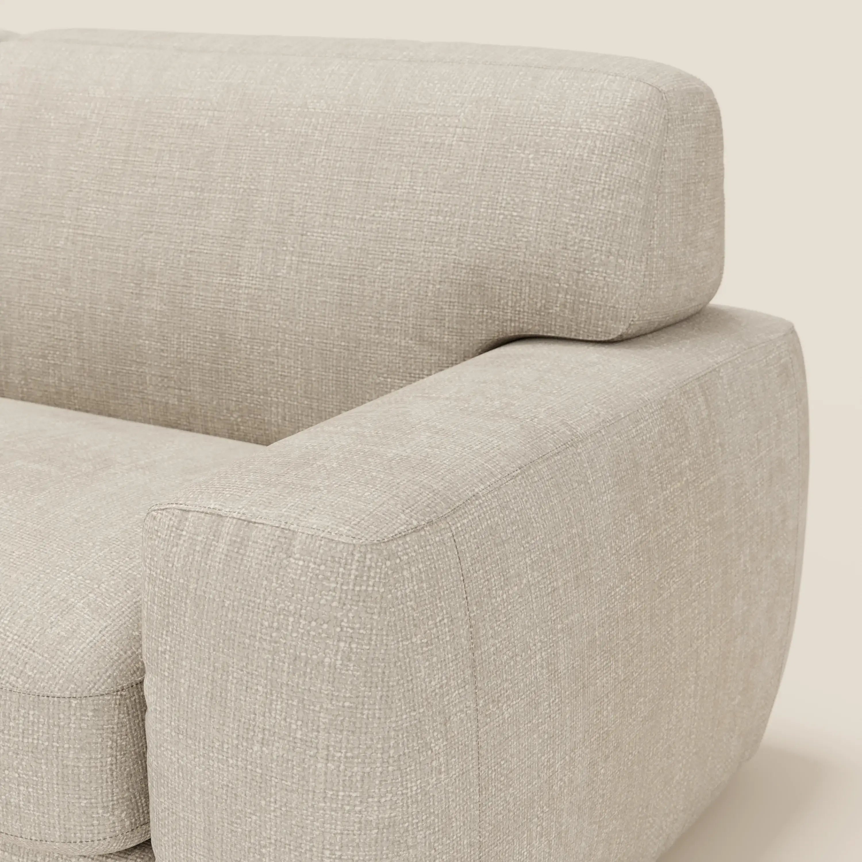 Primo piano del letto materasso Cloud Divano H17 cm di Divani.Store, caratterizzato da un morbido tessuto panna T06 impermeabile, un'imbottitura soffice e un aspetto intrecciato. I dettagli del bracciolo e dello schienale spiccano sullo sfondo chiaro e neutro.