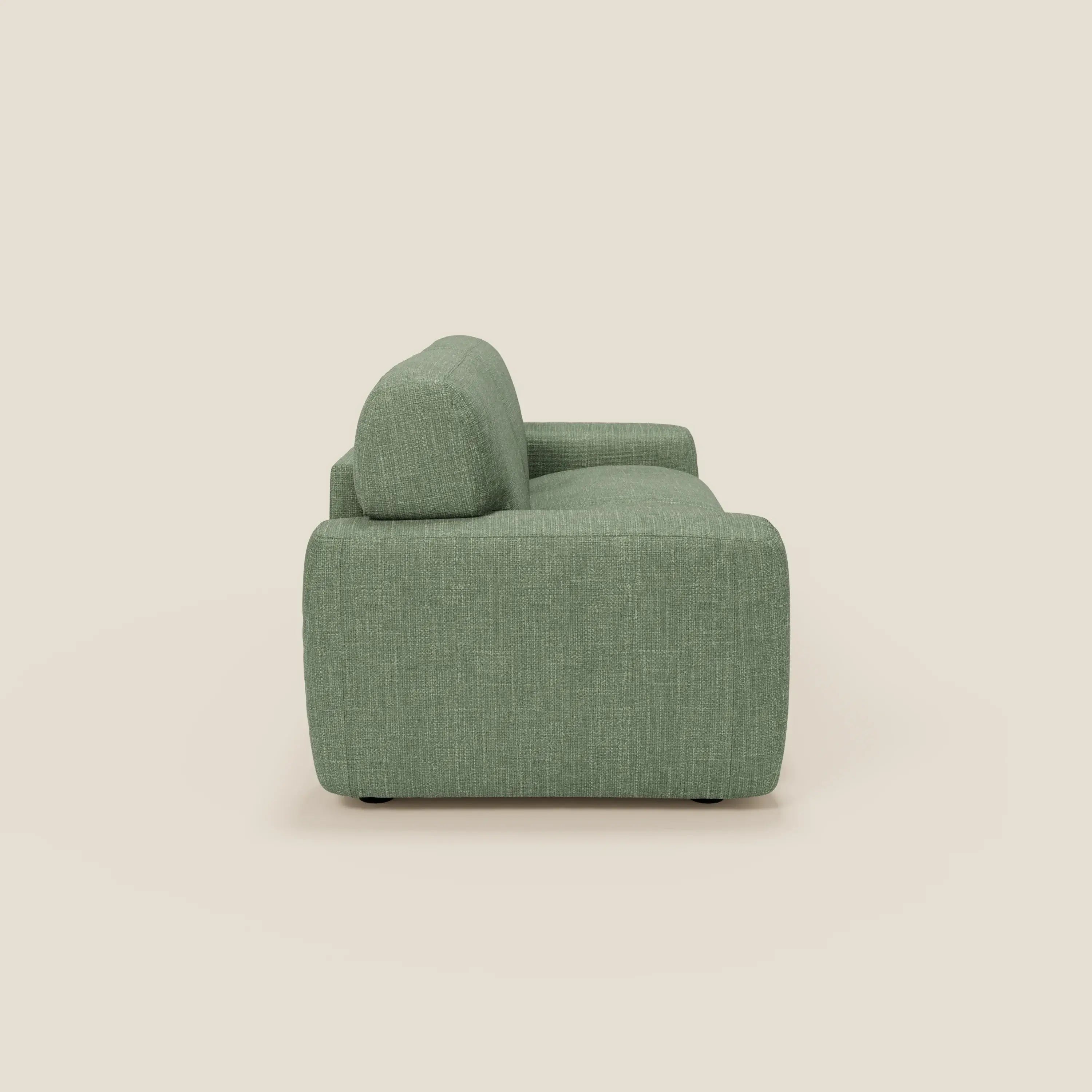 Una vista laterale di Cloud Divano letto materasso H17 cm di Divani.Store, in tessuto impermeabile verde chiaro T06, caratterizzato da una moderna forma rettangolare con bordi arrotondati, schienale basso e ampio bracciolo su uno sfondo bianco sporco.