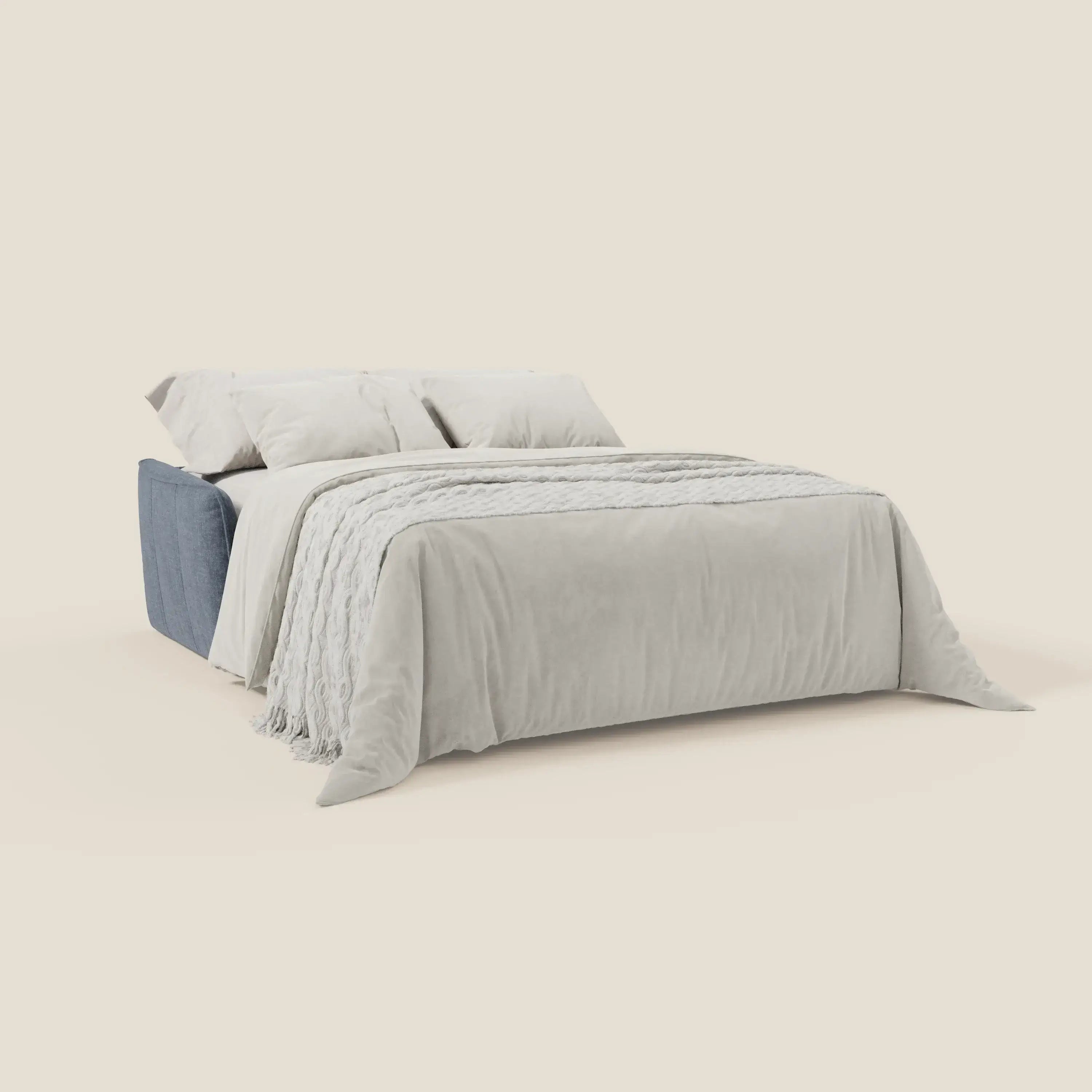 Il divano letto Elios di Divani.Store è caratterizzato da una base in tessuto antimacchia ardesia T24 blu, morbidi cuscini in spalliera, lenzuola bianche, due grandi cuscini bianchi e una coperta grigio chiaro per un look pulito e minimale su uno sfondo beige.