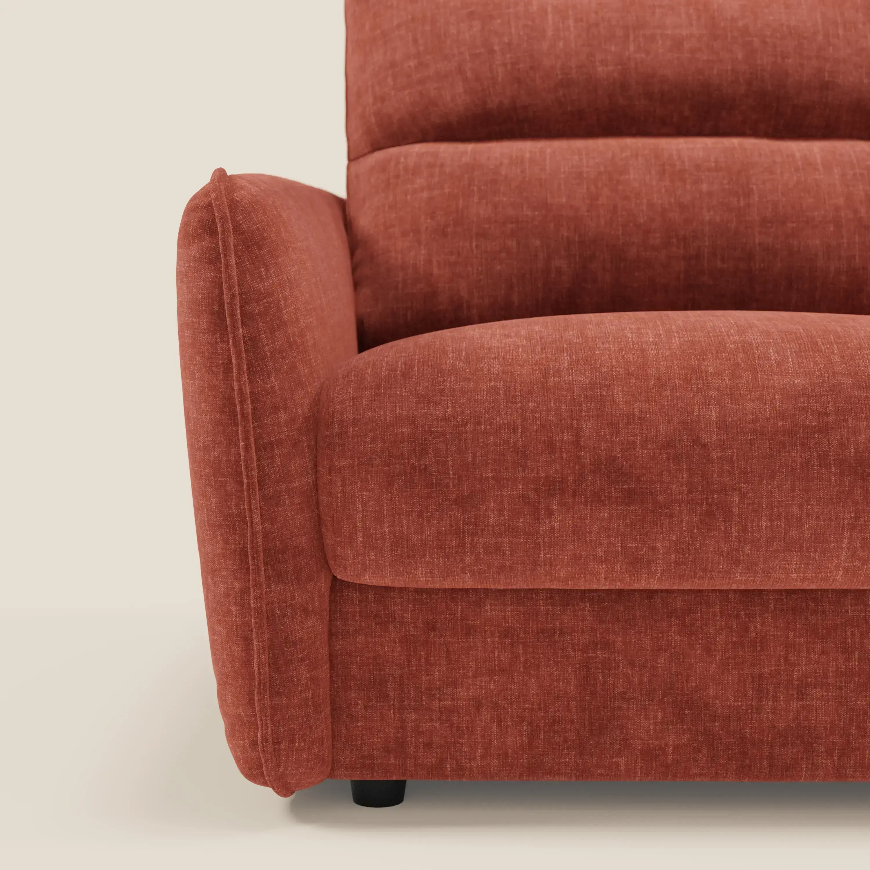 Primo piano del divano letto Elios di Divani.Store in T24 ruggine tessuto smacchiabile, che mostra il bracciolo, la spalliera in cuscini morbidi e le cuciture verticali. Il divano poggia su gambe corte e scure su uno sfondo neutro.