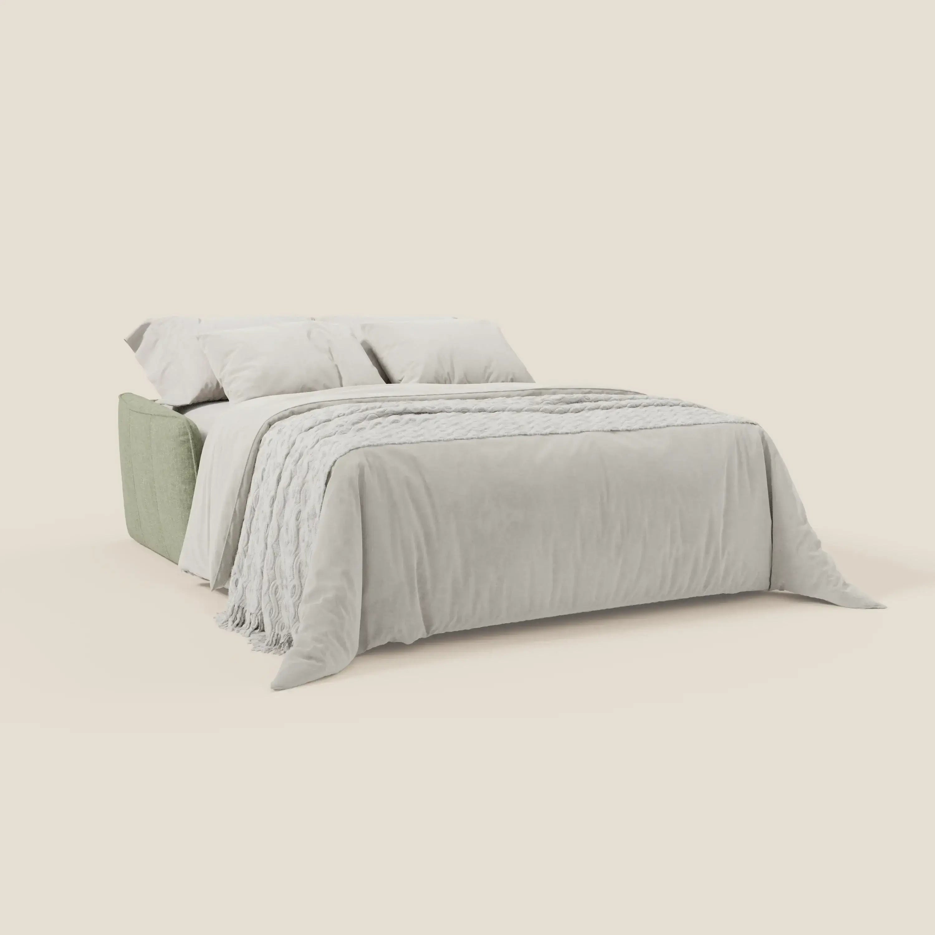 Elegante letto di Divani.Store, Elios Divano letto è caratterizzato da morbidi cuscini di schienale e da una testiera in tessuto antimacchia T24 verde salvia, completata da un piumone grigio chiaro e da cuscini coordinati su uno sfondo bianco sporco.