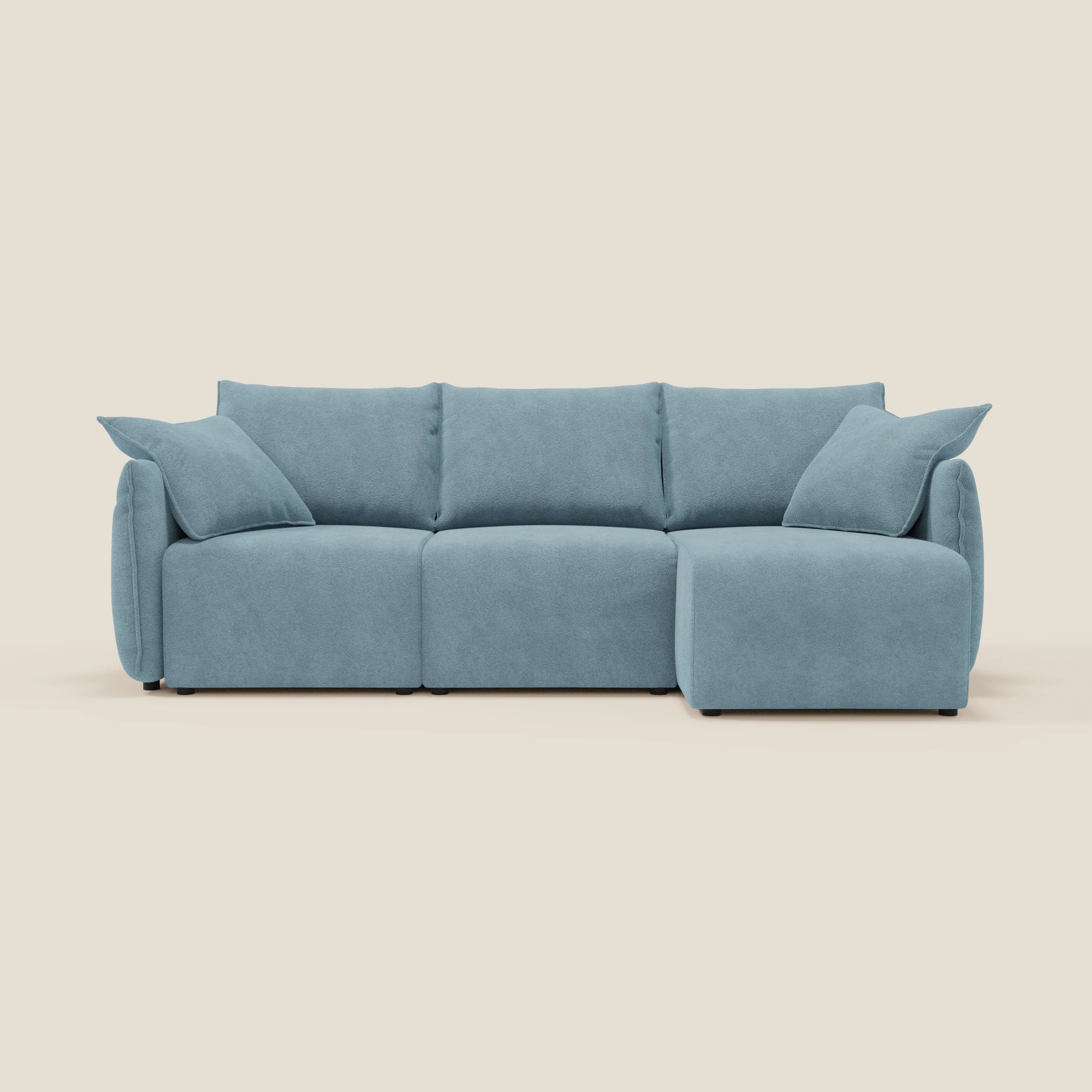 Il Flexar Divano angolare reversibile di Divani.Store in morbido bouclé impermeabile T07 carta da zucchero è caratterizzato da sedute allungabili, tre cuscini per lo schienale, due grandi cuscini per i braccioli e una chaise lounge destra su gambe a blocco su sfondo beige.