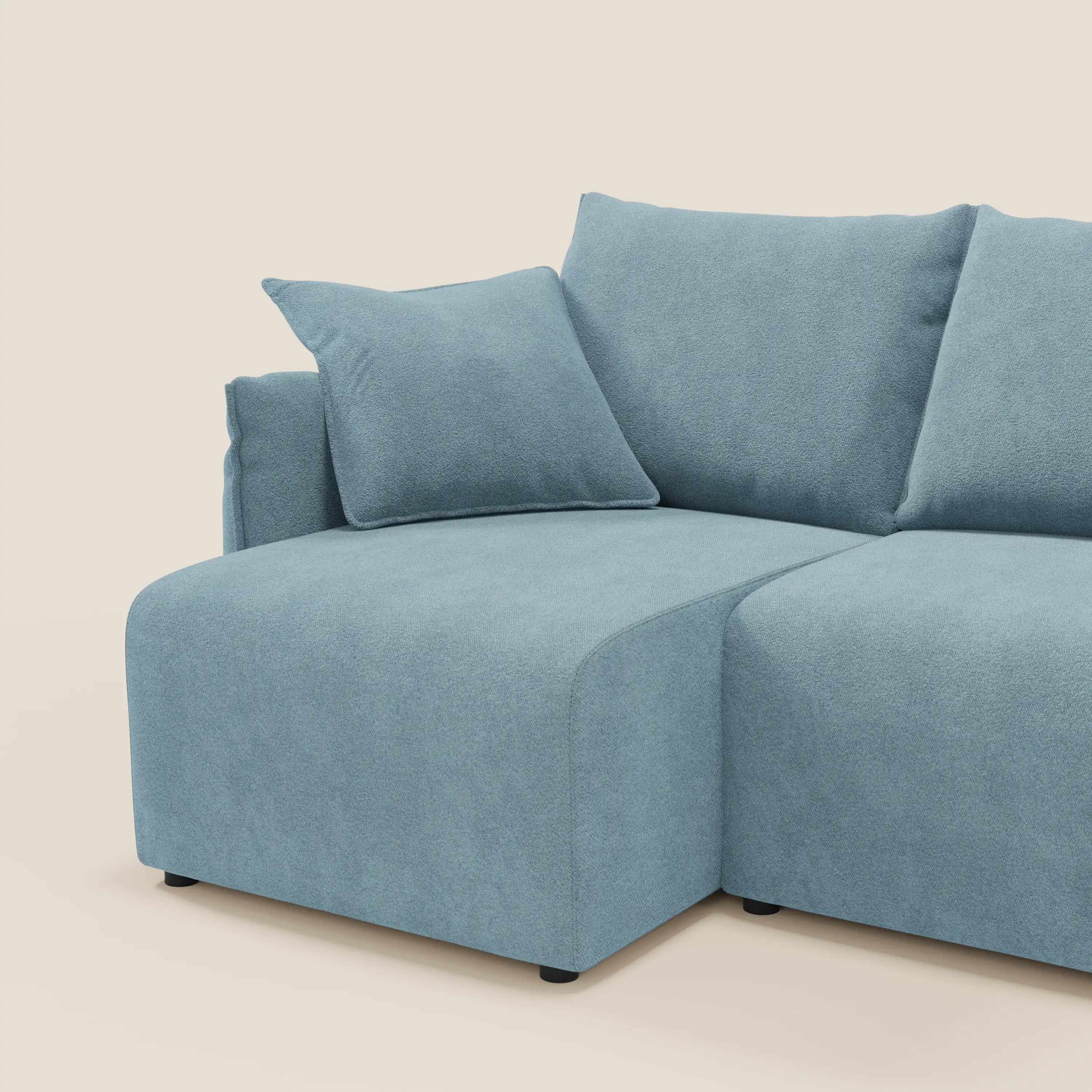 Il Flexar Divano angolare reversibile di Divani.Store in morbido bouclé impermeabile T07 carta da zucchero è dotato di chaise lounge, bracciolo quadrato, cuscini in piuma d'oca e cuscino coordinato su sfondo bianco sporco.