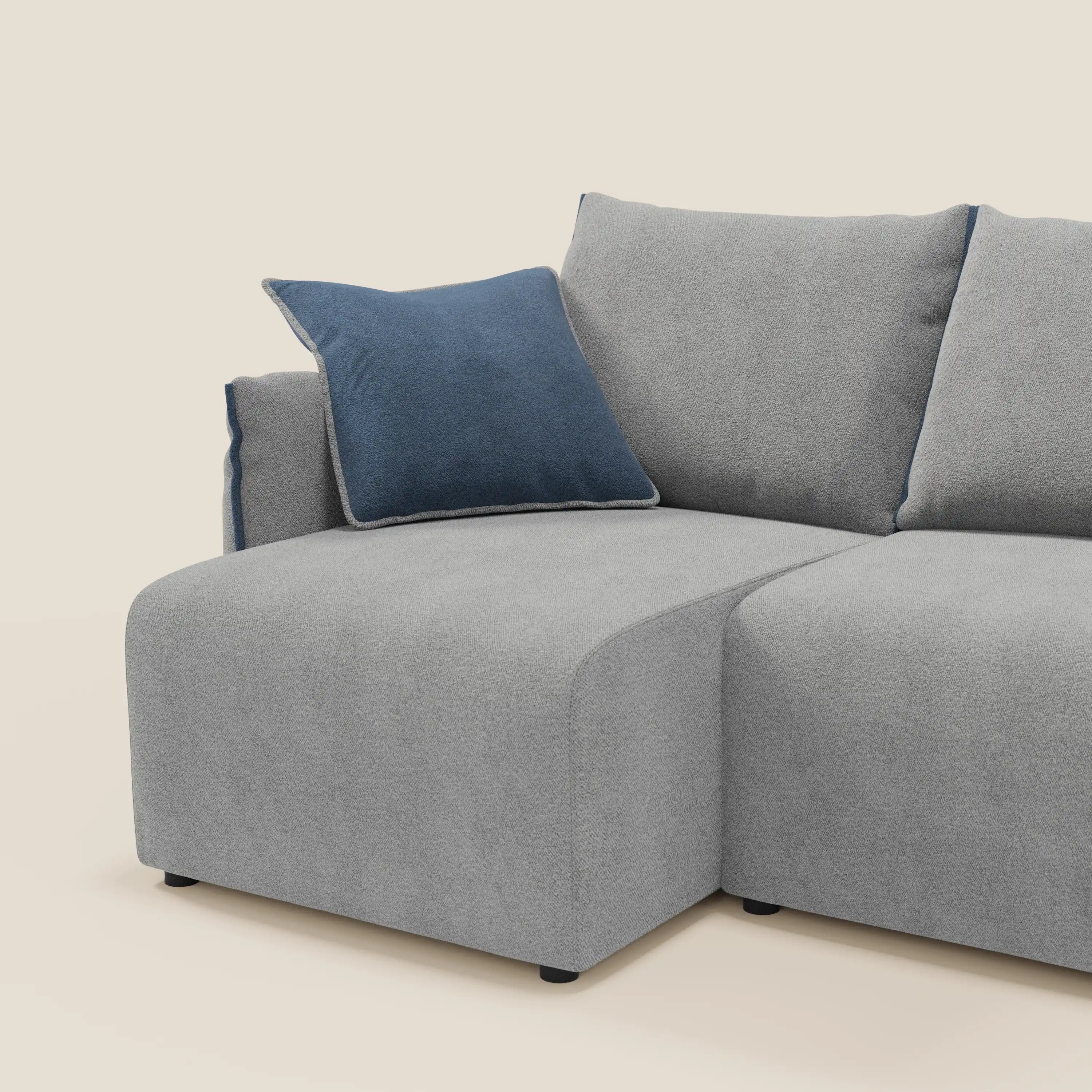 Flexar Divano angolare reversibile di Divani.Store è caratterizzato da bordi morbidi e arrotondati, da una seduta profonda in bouclé impermeabile grigio chiaro T07 e da un cuscino blu scuro. Le linee pulite e la modularità reversibile completano il look minimalista.