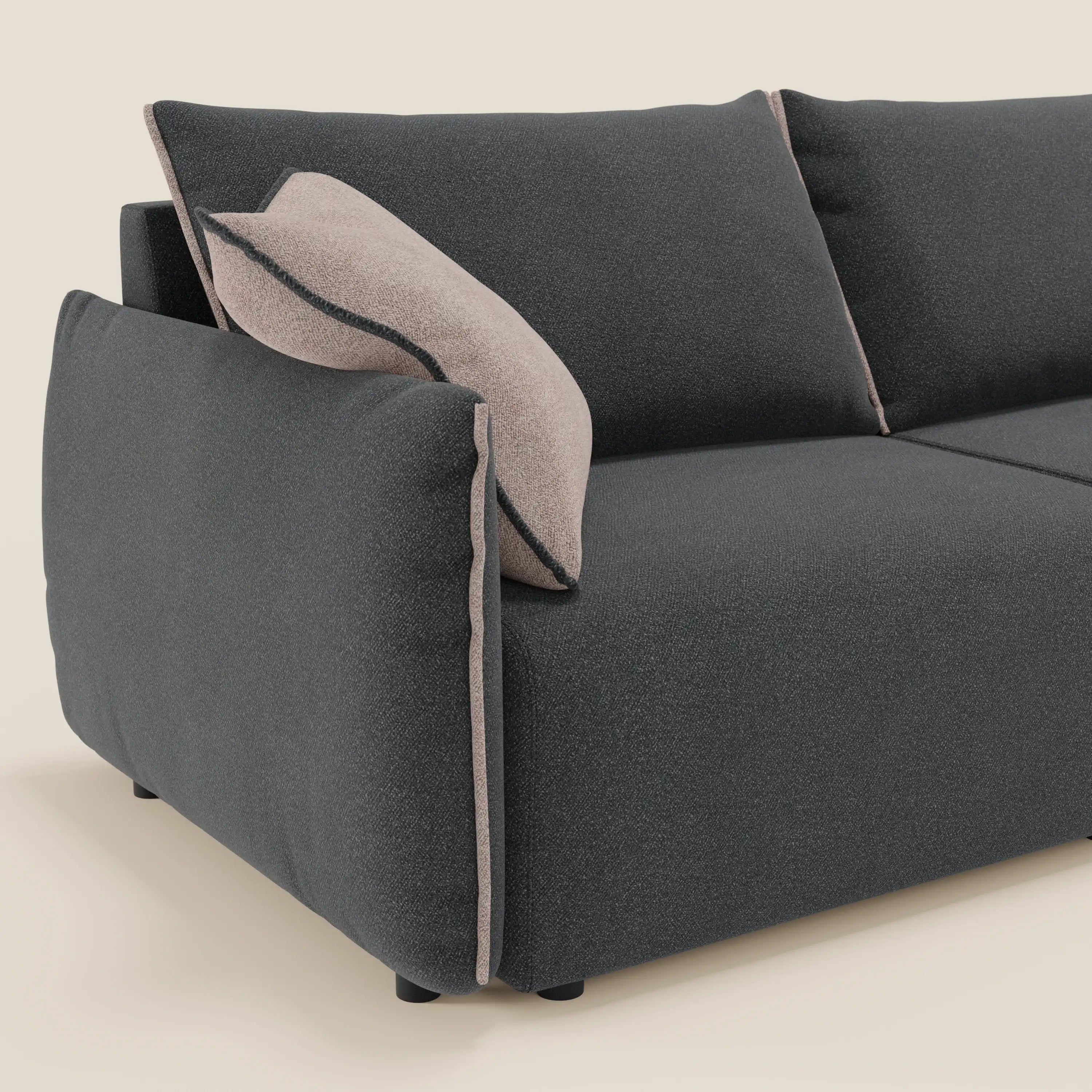 Un primo piano del divano Flexar di Divani.Store con sedute allungabili e schienale in piuma in morbido bouclé impermeabile T07 antracite-rosa mostra i cuscini morbidi e il comfort personalizzabile. Un cuscino coordinato con bordi scuri si appoggia al bracciolo.